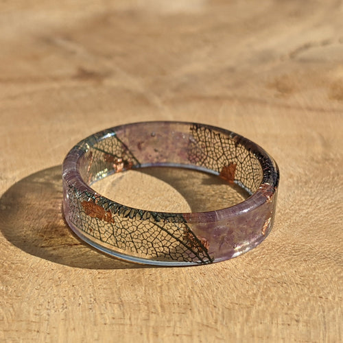 Glass band ring with leaf patterns on a wooden surface