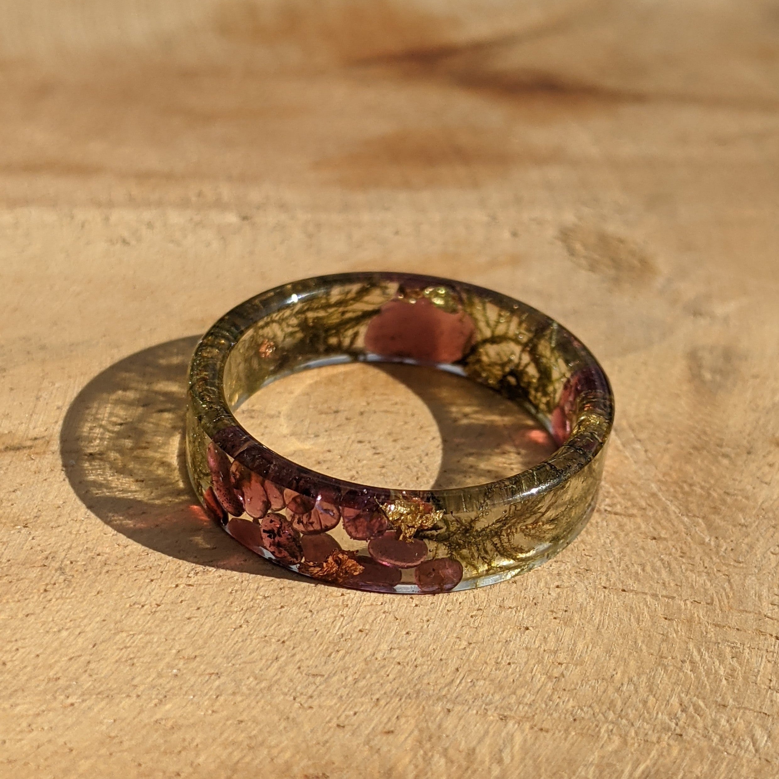Round resin coaster with leaf pattern on a wooden surface