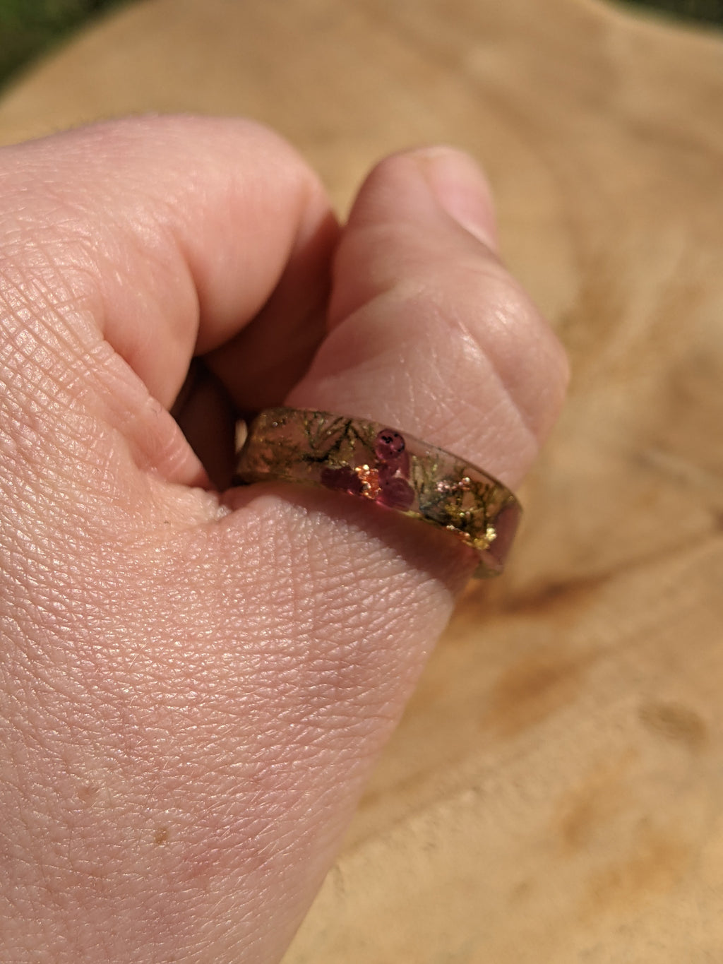 Hand wearing a ring with a clear stone on a wooden surface