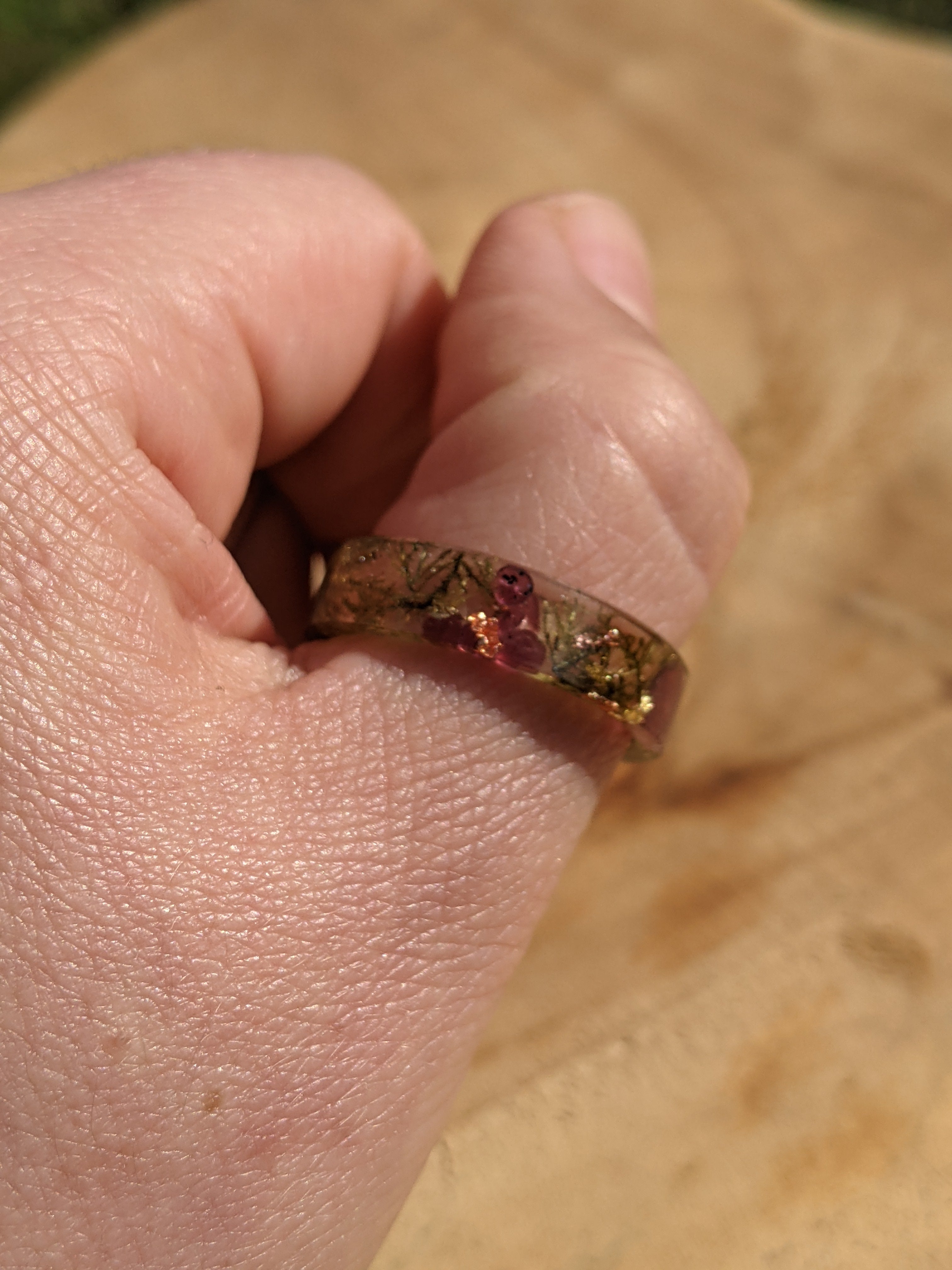 Hand wearing a ring with a clear stone on a wooden surface