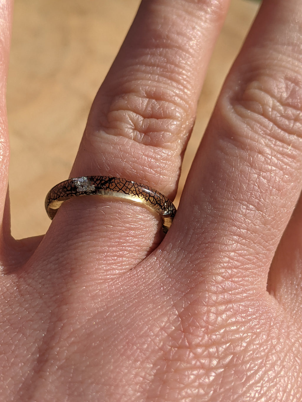 Close-up of a hand wearing a gold ring with a textured band.