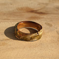 Gold ring on a textured beige surface