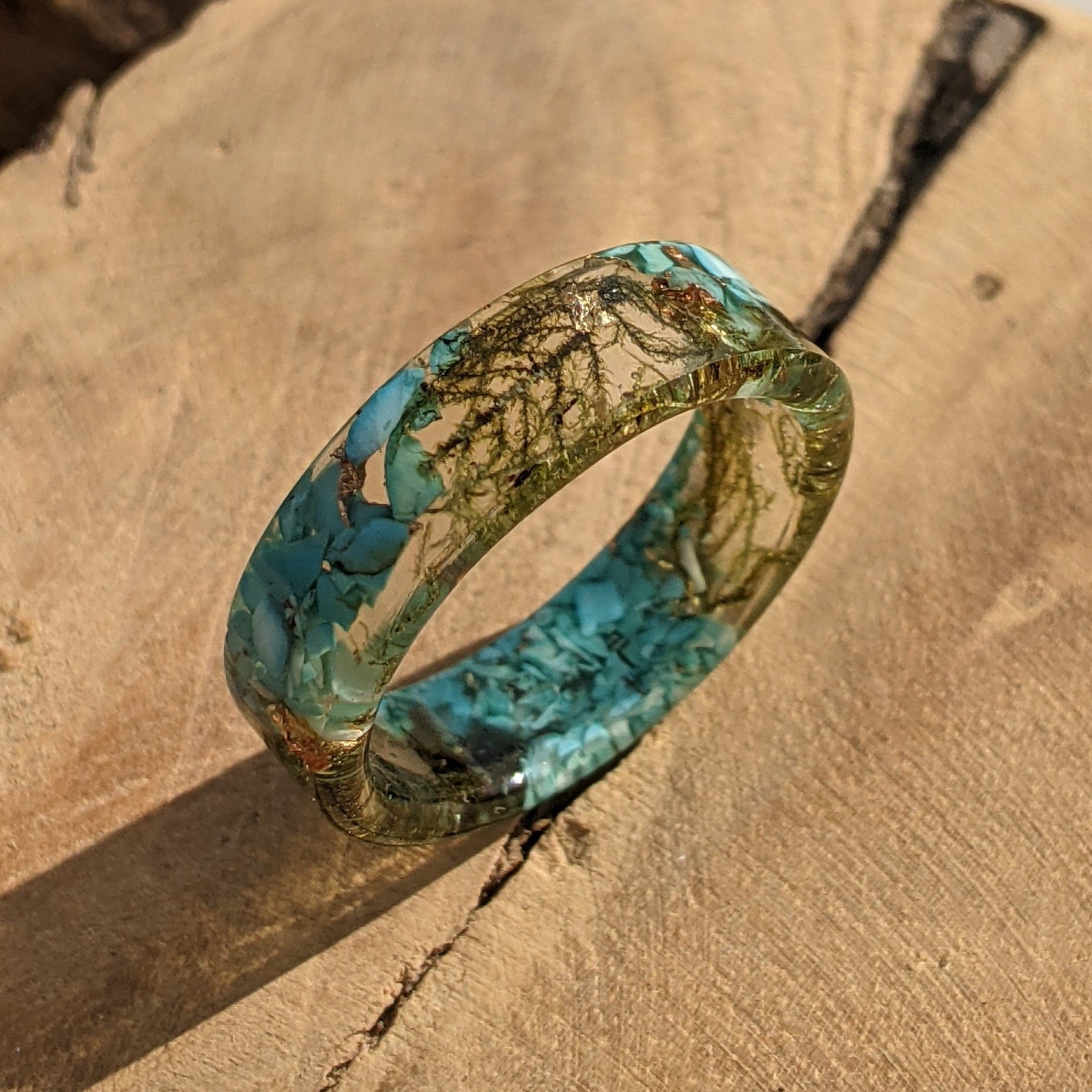 Turquoise and gold ring on a textured brown surface