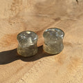 Two clear stone plugs on a wooden surface