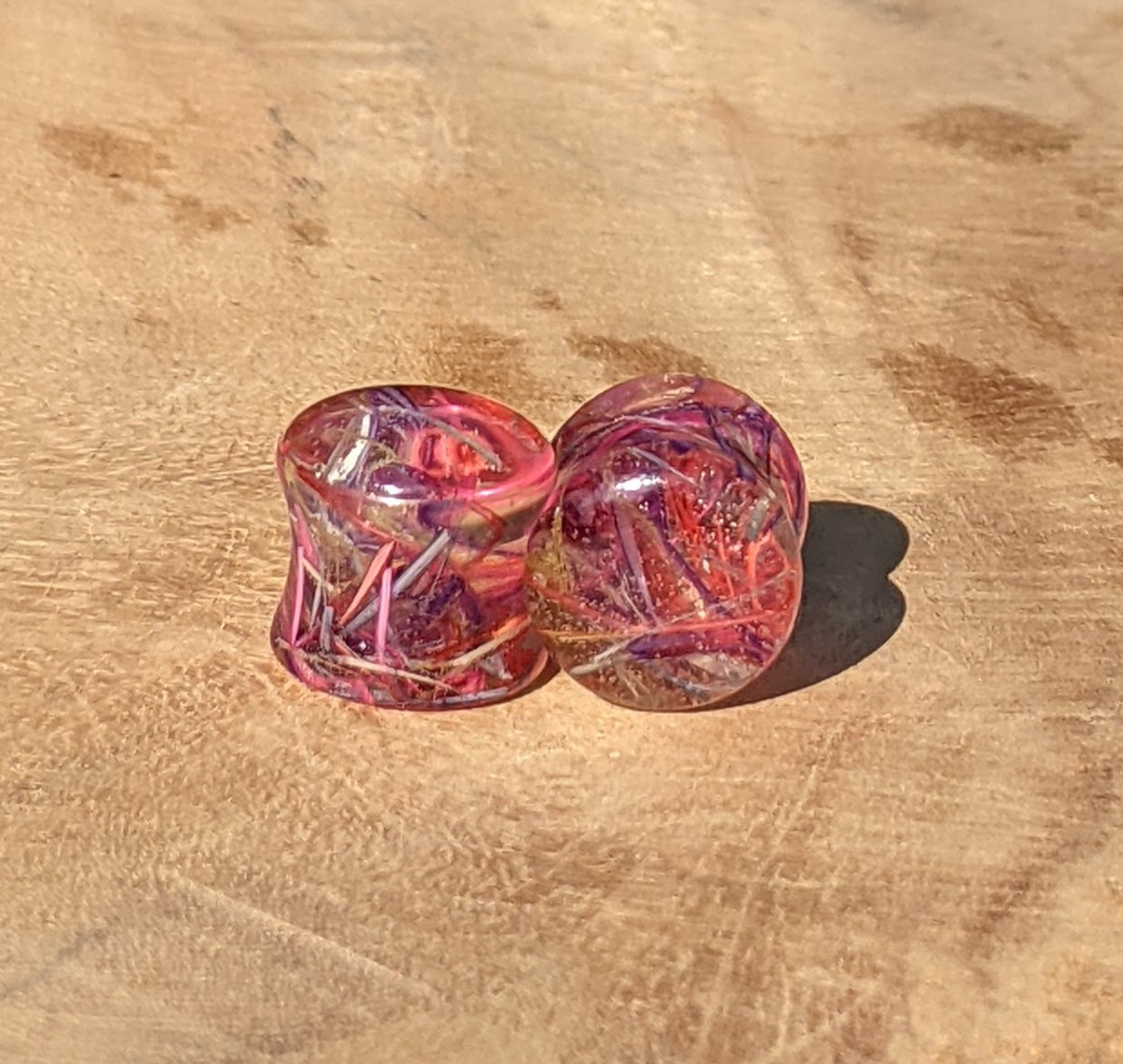 Close up of real rainbow feathers preserved in clear resin ear plugs EL-Creations