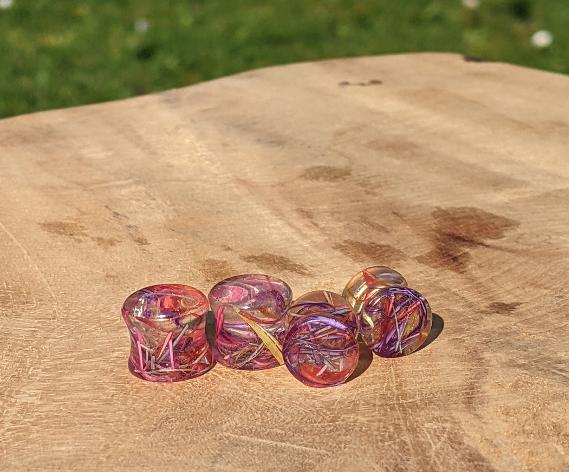 Set of colorful glass beads on a wooden surface with a grassy background