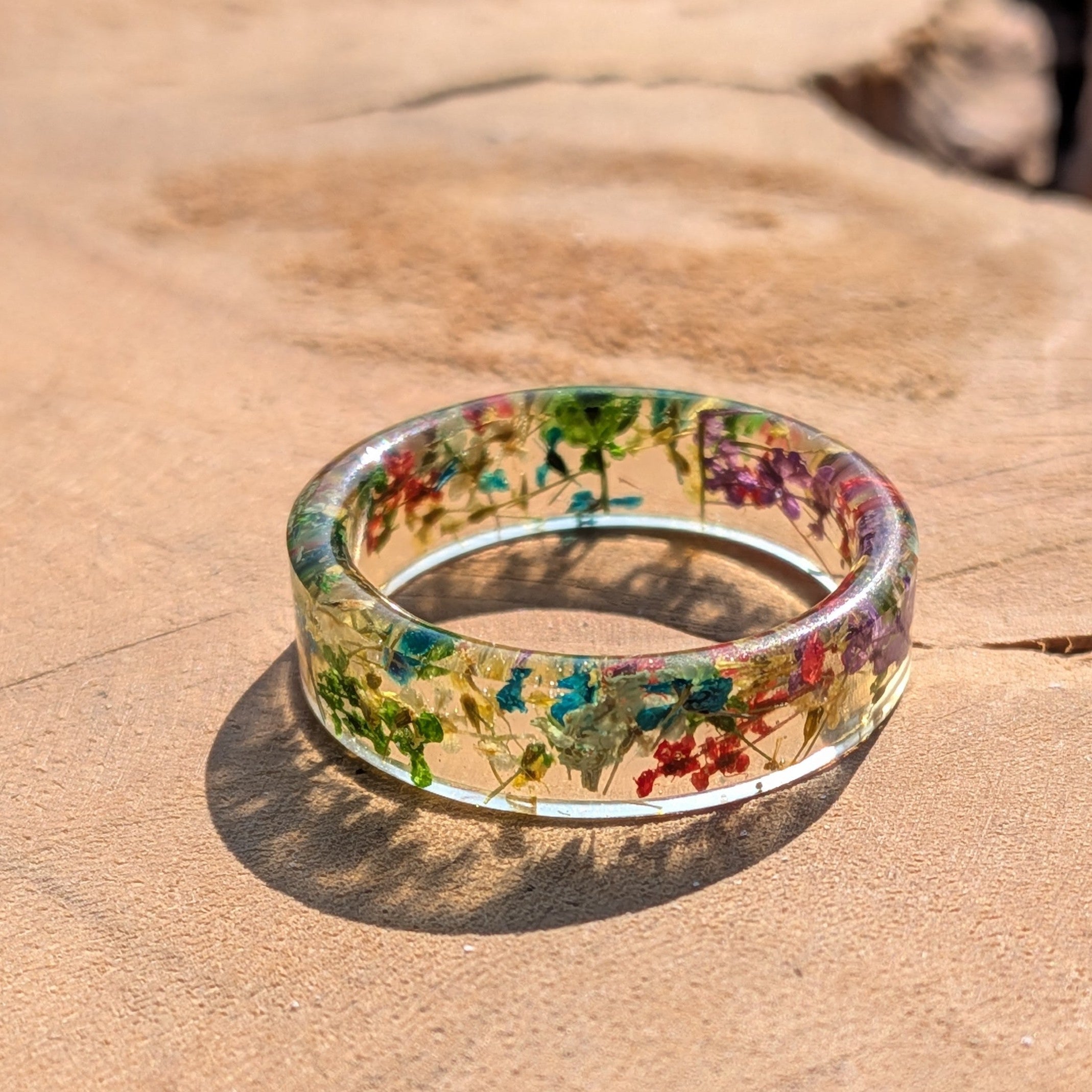 Clear ring with embedded colorful flowers on a wooden surface