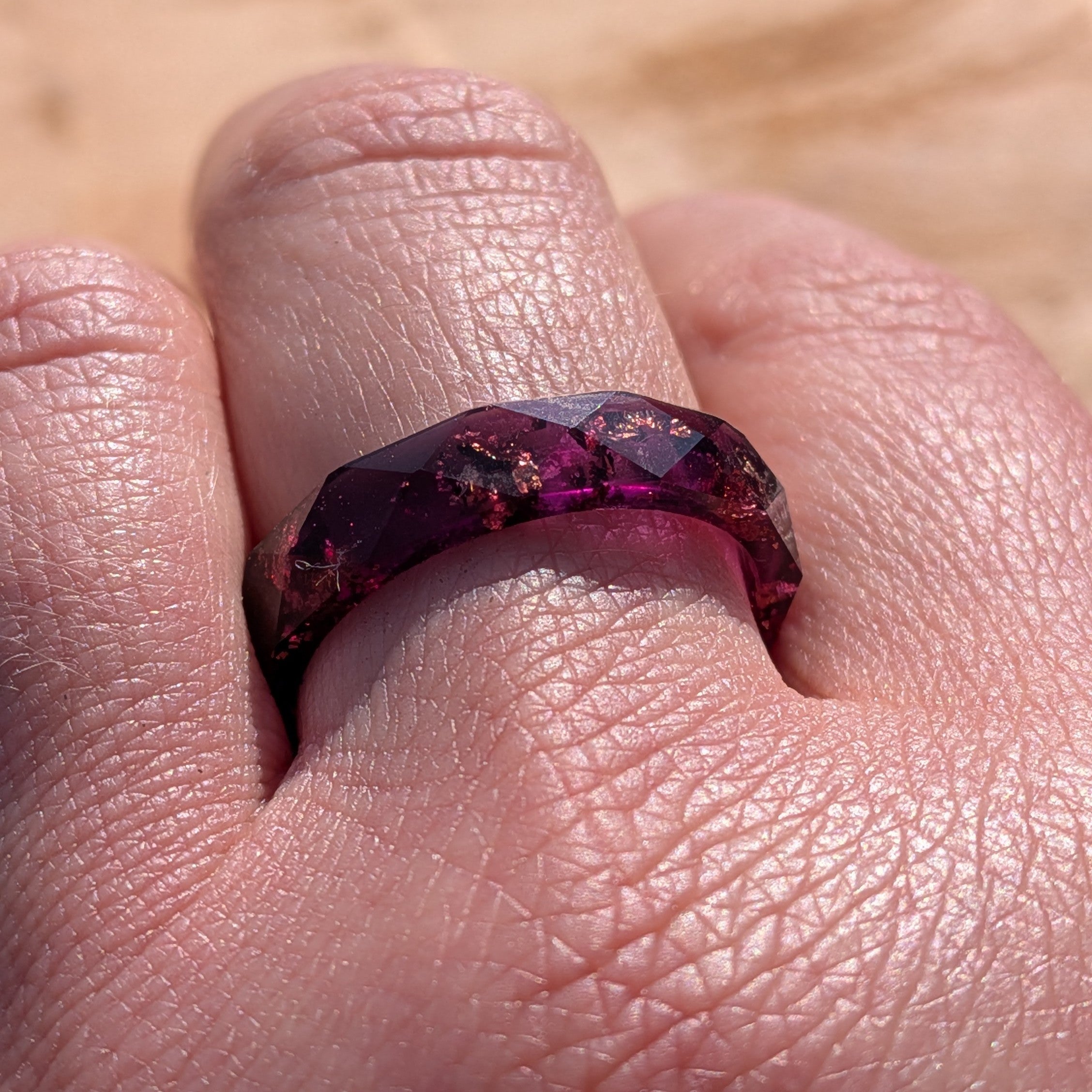 Close-up of a hand wearing a purple gemstone ring.