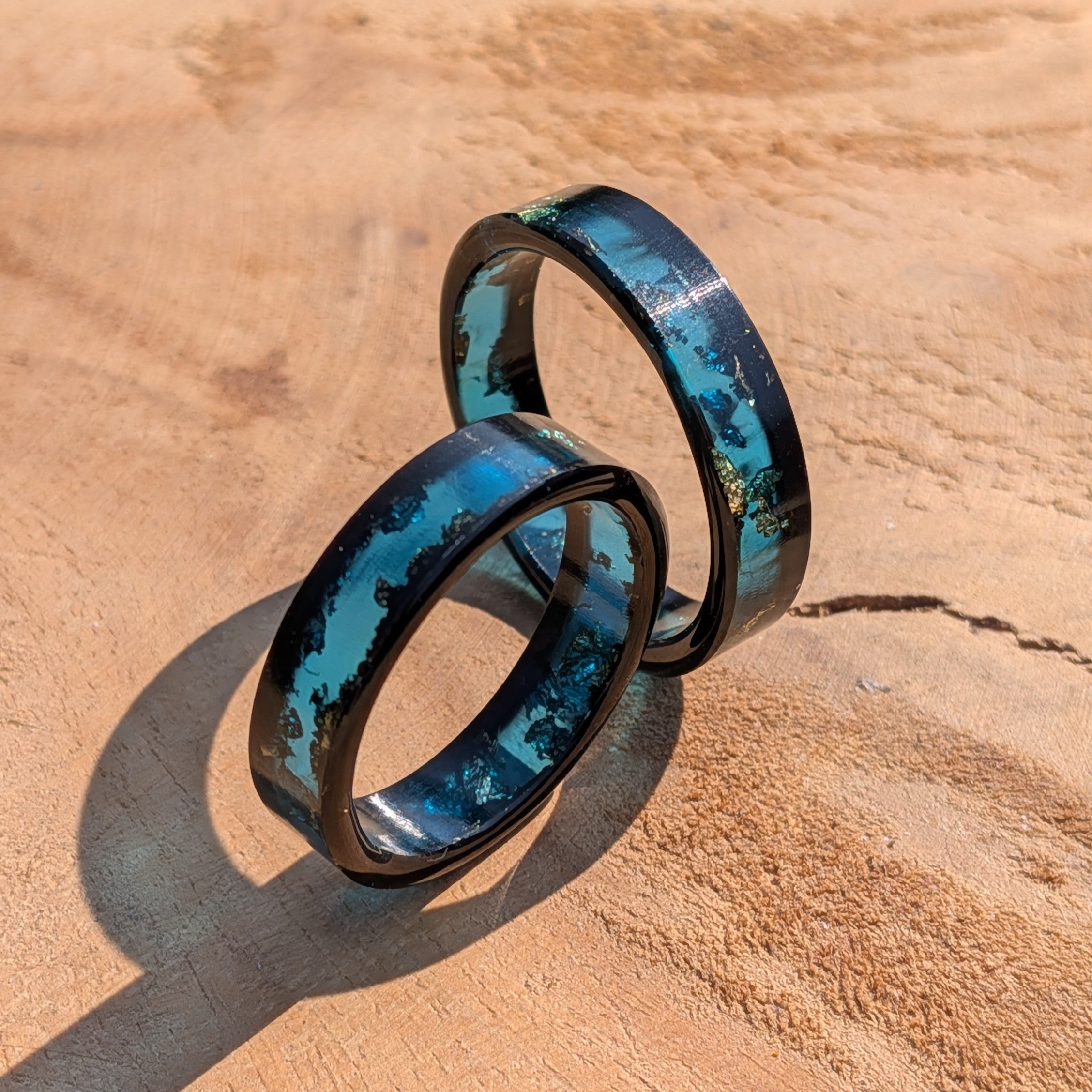 Two blue and black men rings on a wooden surface