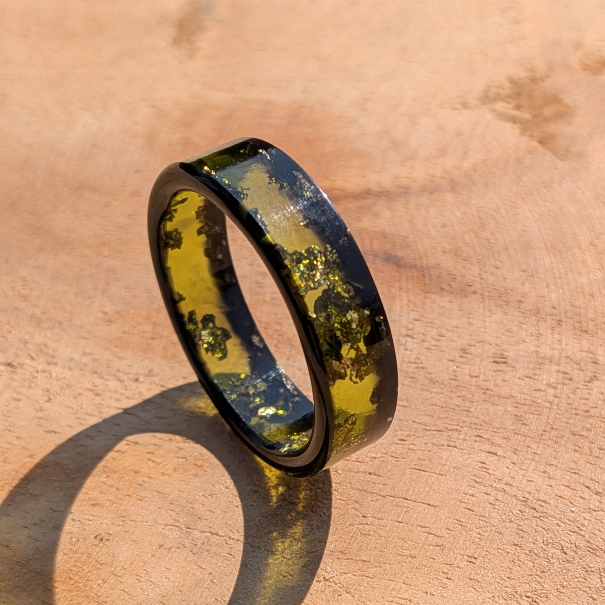 Ring with embedded green material on a wooden surface