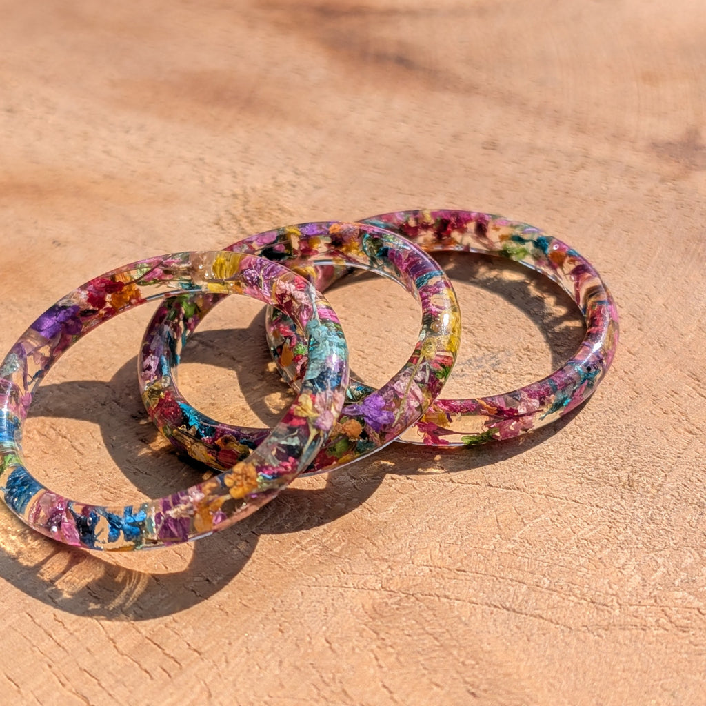 Colorful floral-patterned resin rings on a wooden surface