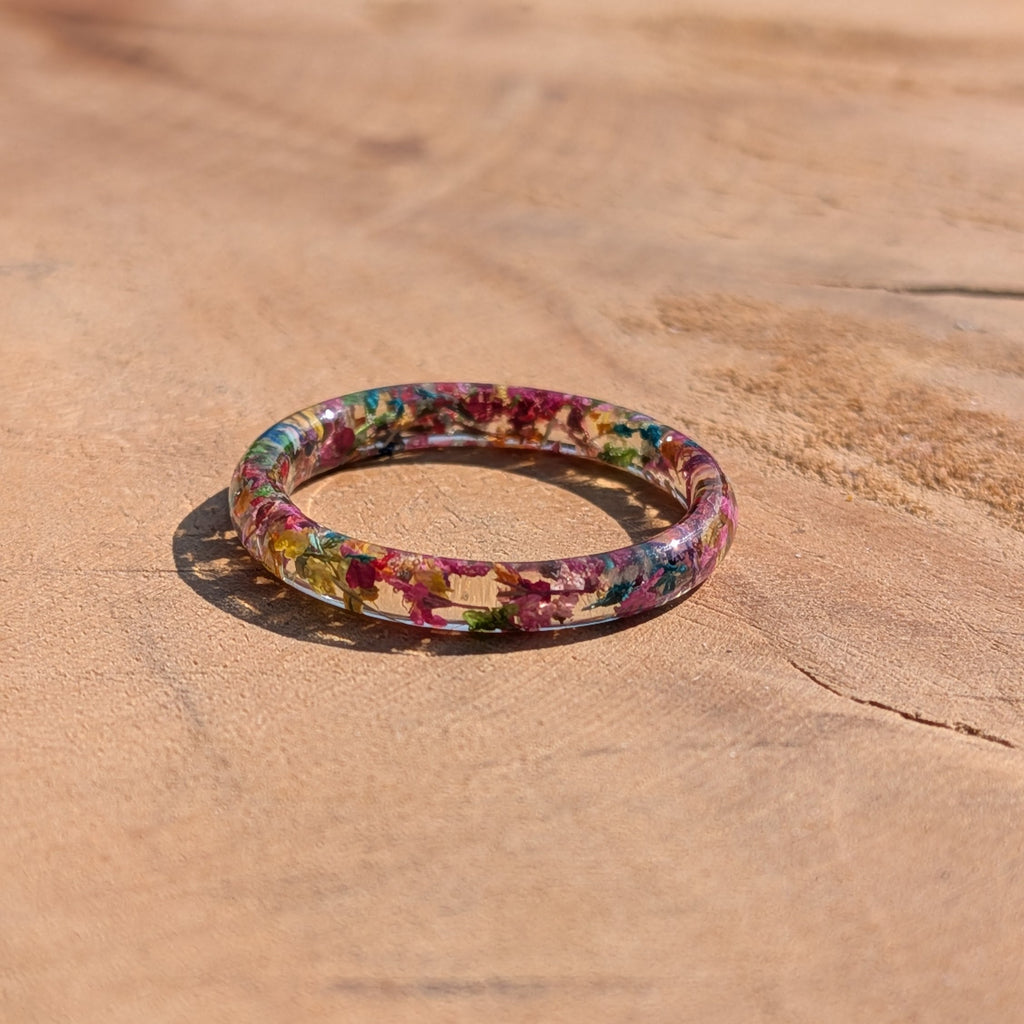 Multicolored floral resin ring on a wooden surface