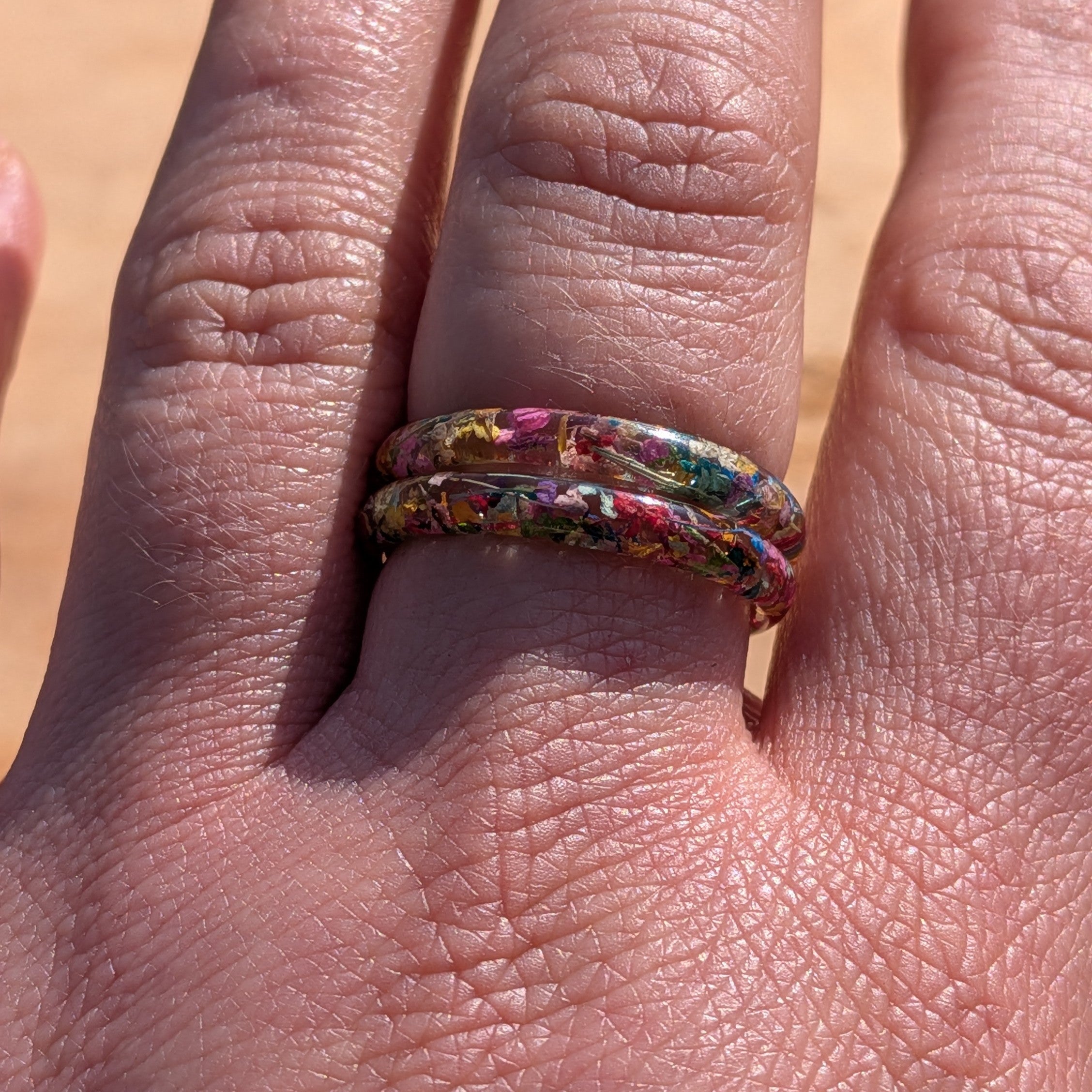 Multicolored ring on a finger with a neutral background