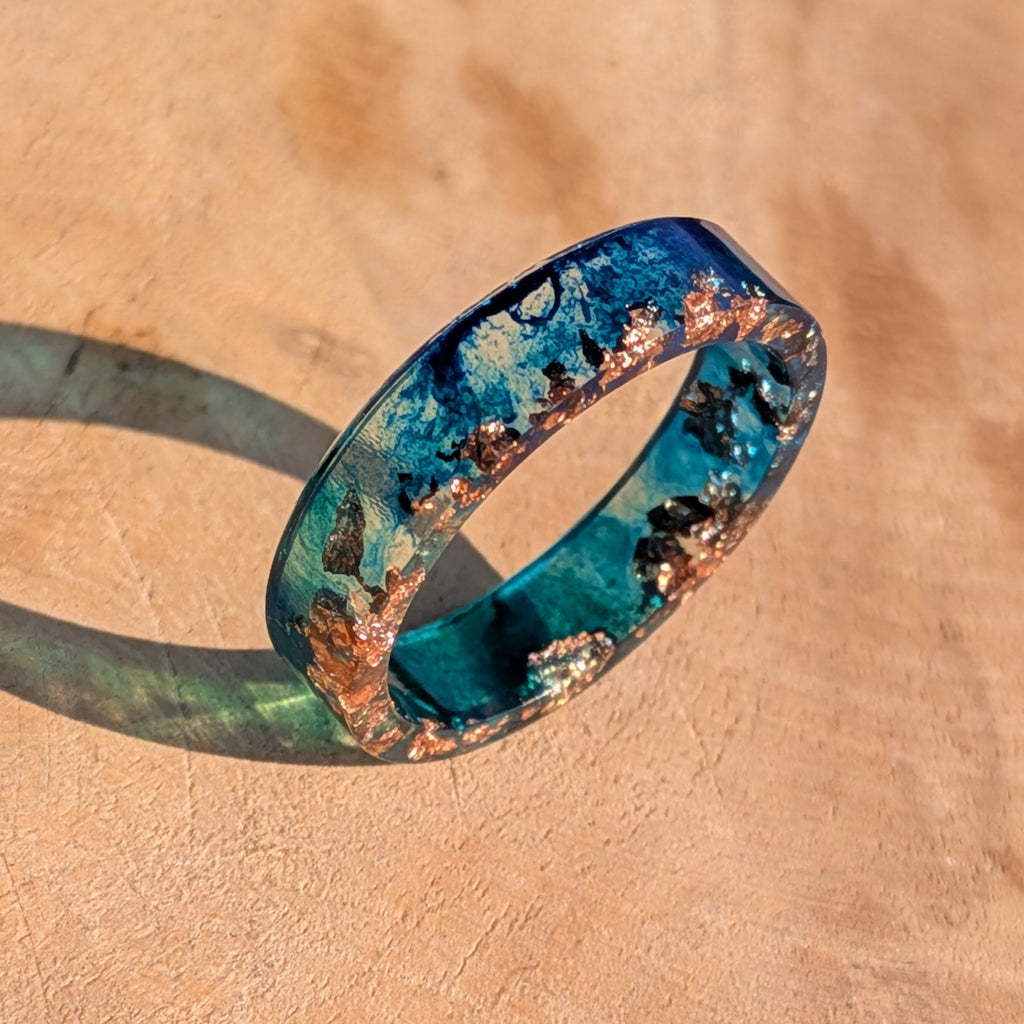 Blue and bronze ring on a beige surface
