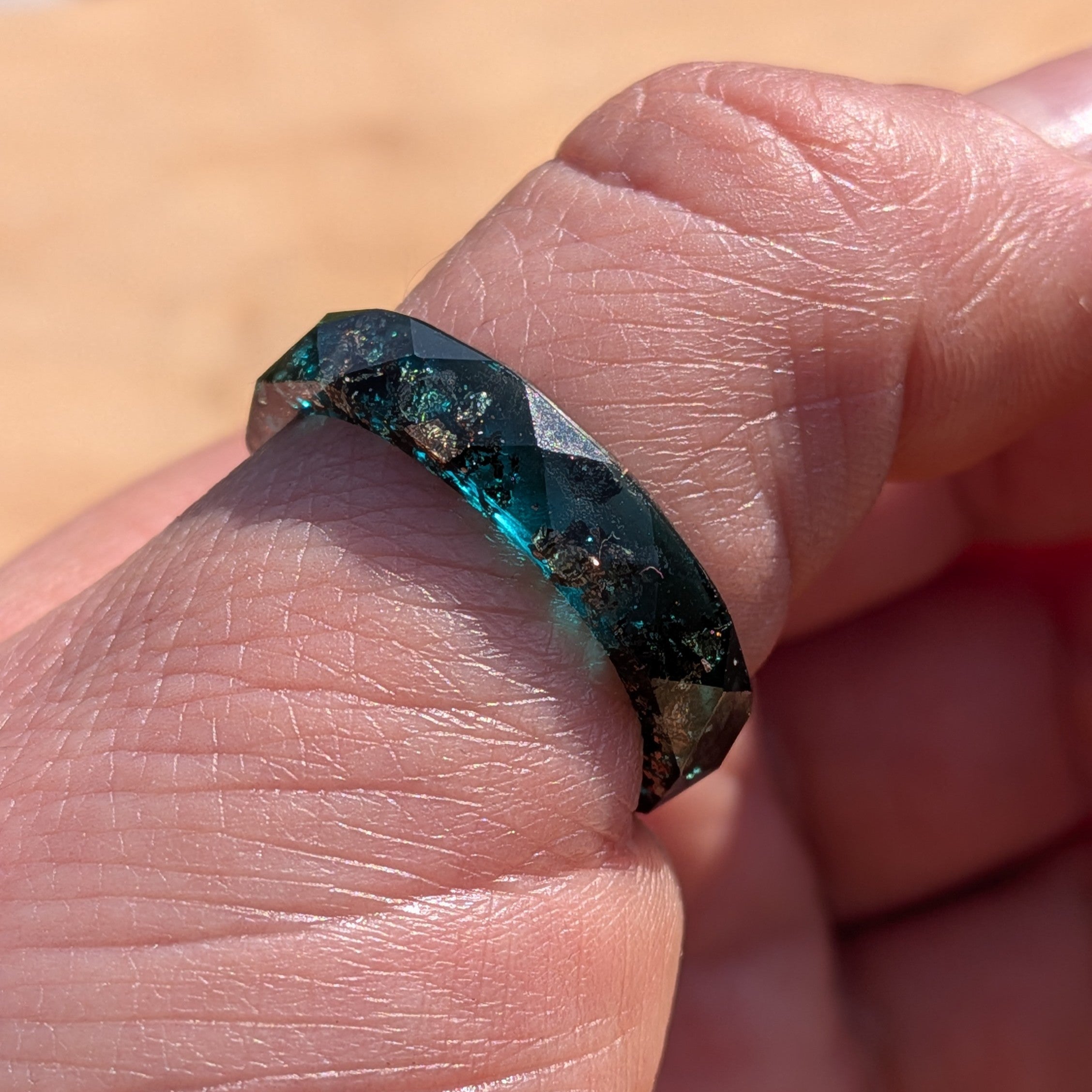 Close-up of a hand wearing a faceted gemstone ring with a blurred background