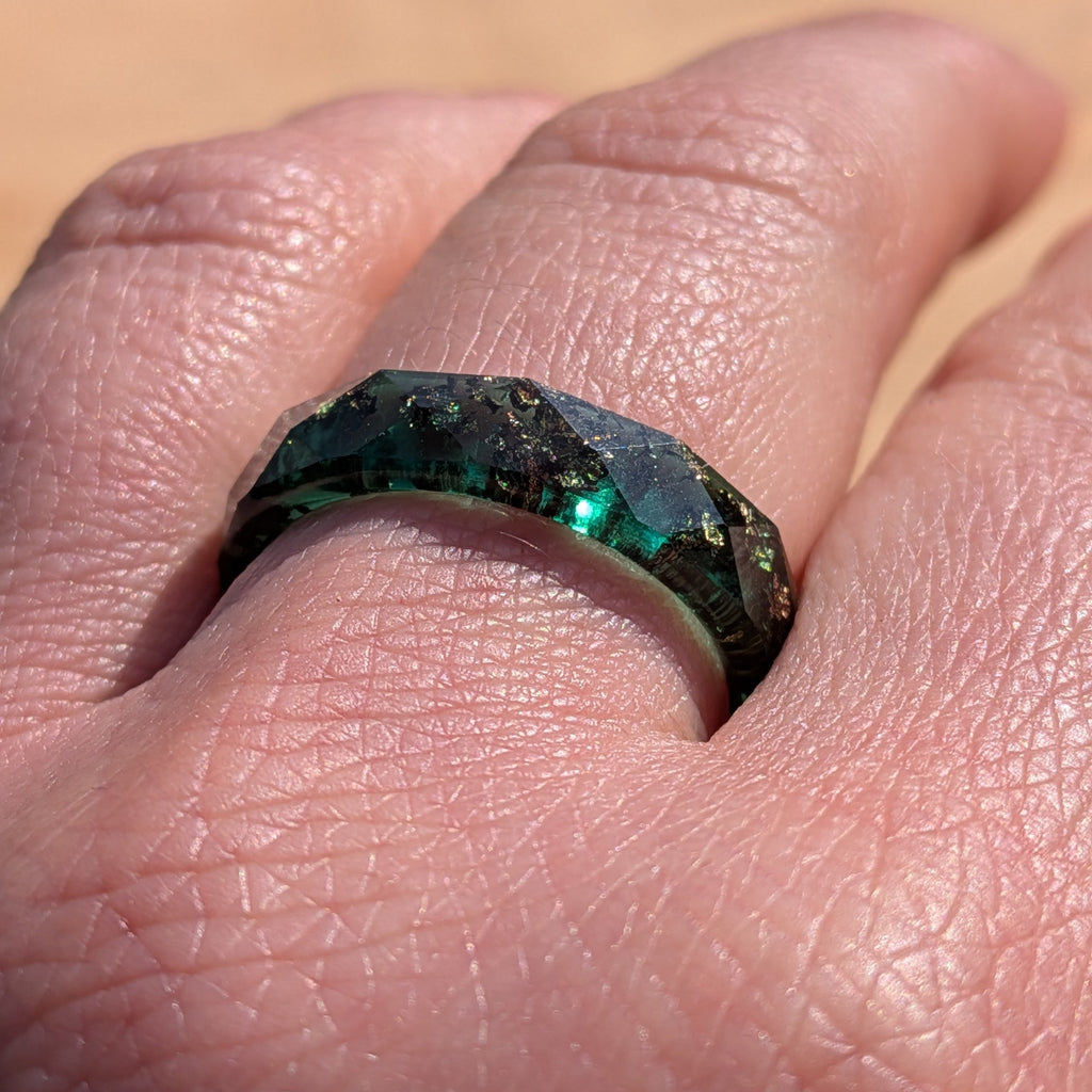 Close-up of a hand wearing a ring with a green gemstone.
