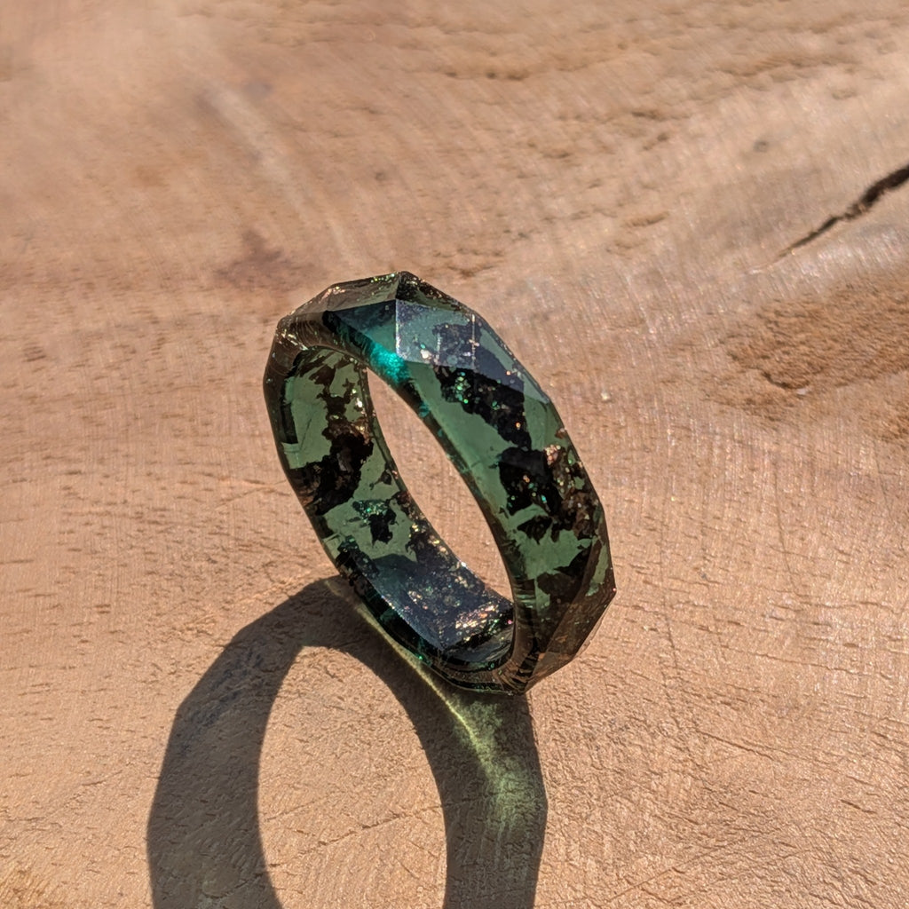 Green and black geometric ring on a wooden surface
