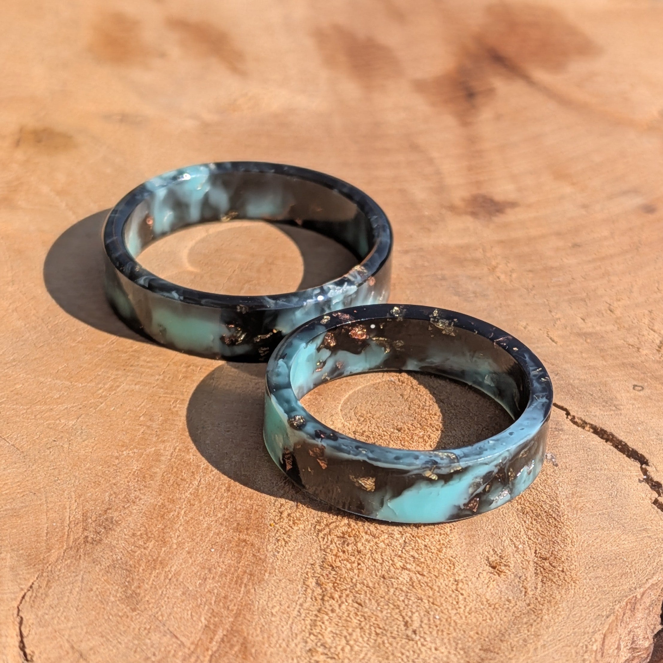 Two turquoise and black rings on a wooden surface
