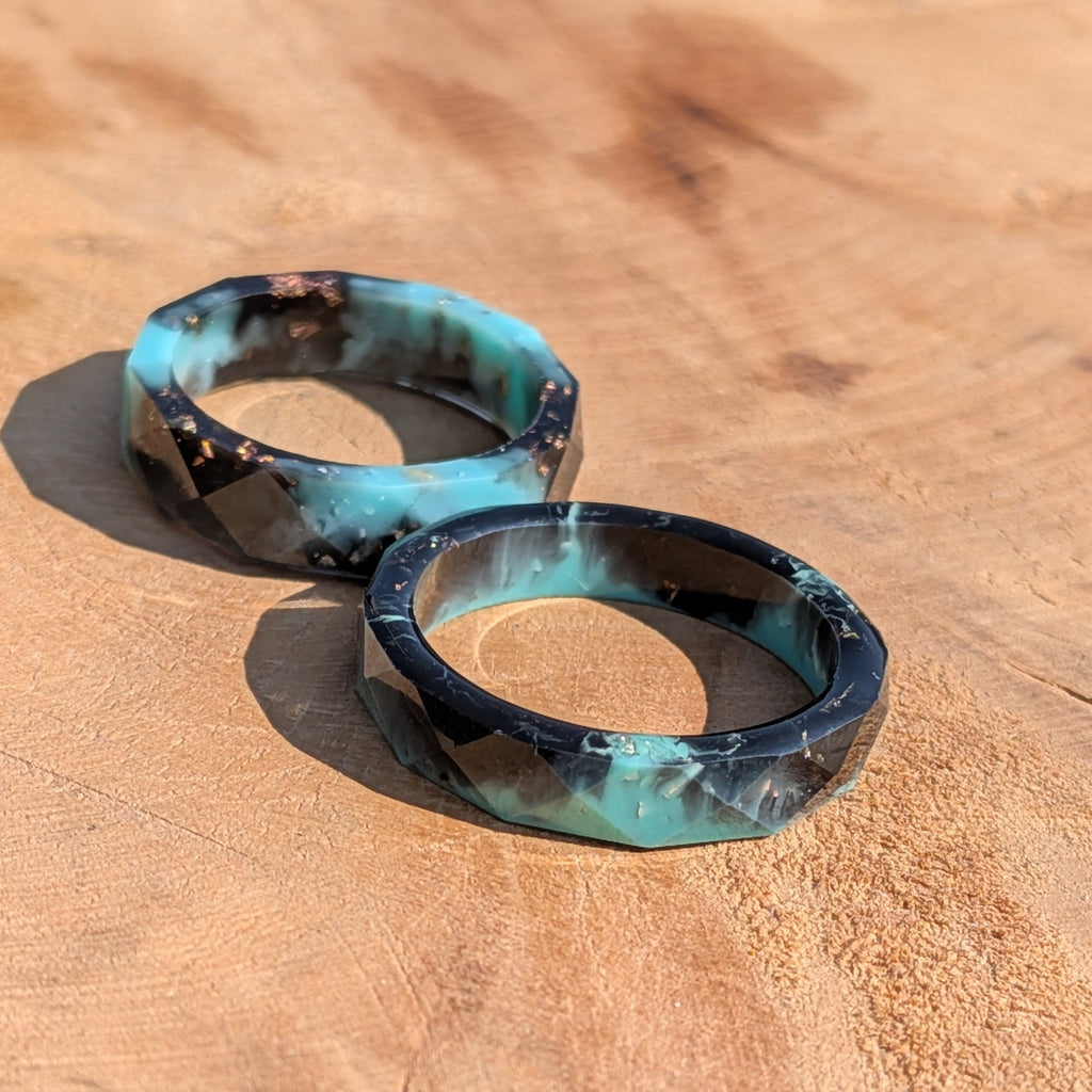 Two turquoise and black rings on a wooden surface