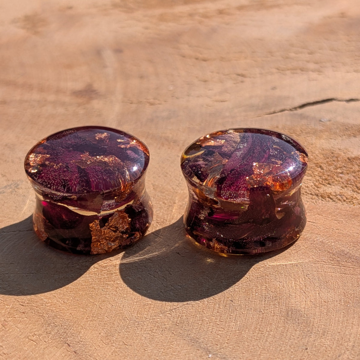 Close up of dried rose and copper flakes inside clear resin ear plugs EL-Creations