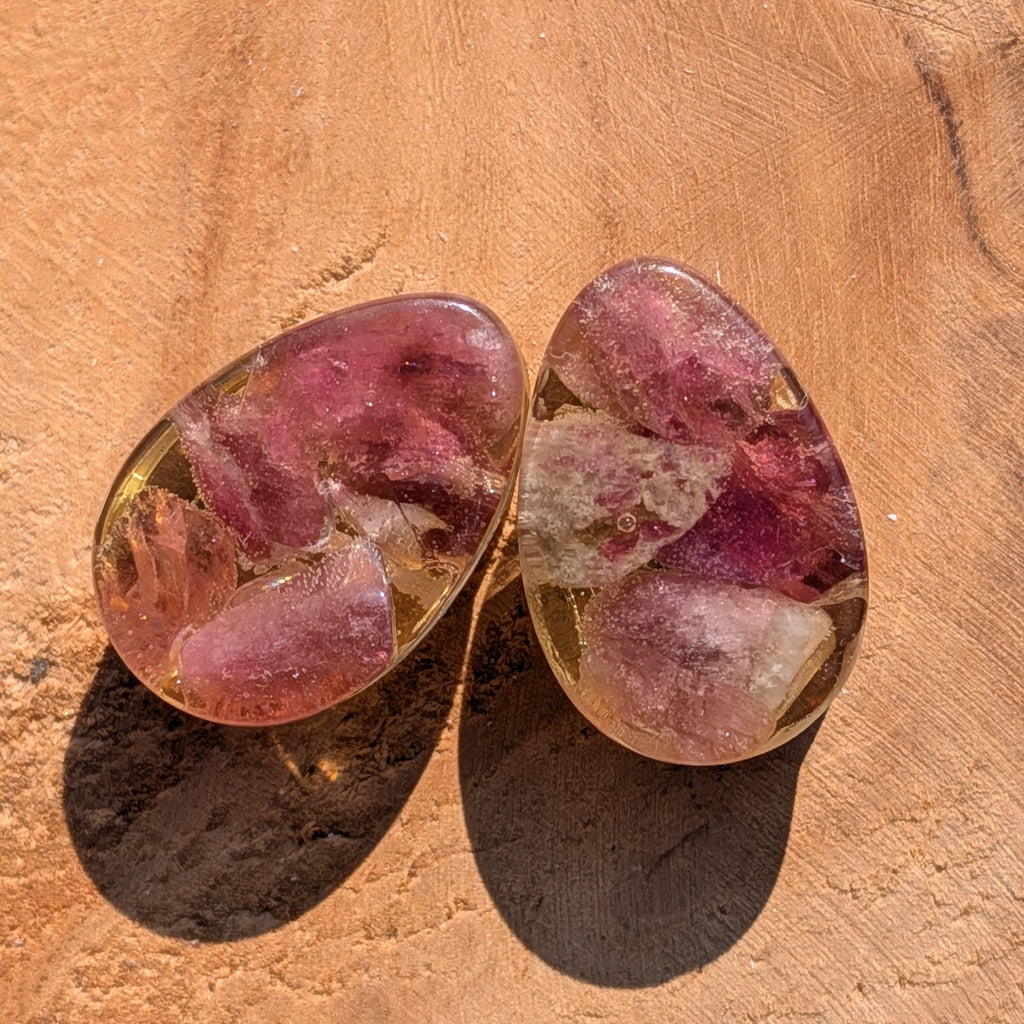 Two pink and clear stone earrings on a wooden surface
