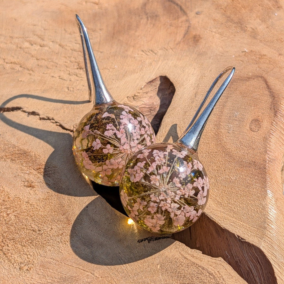 Dried white flower and moss resin ball earrings top view, botanical dangle jewelry handmade in Belgium