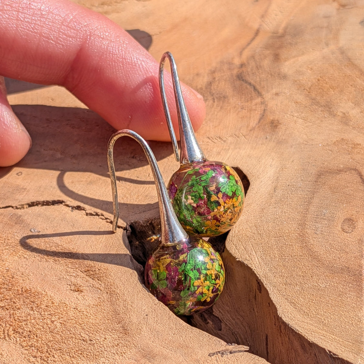 Mixed dried flower and moss resin ball earrings top view, botanical dangle jewelry handmade in Belgium
