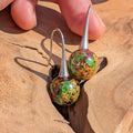 Pair of earrings with floral design on a wooden surface
