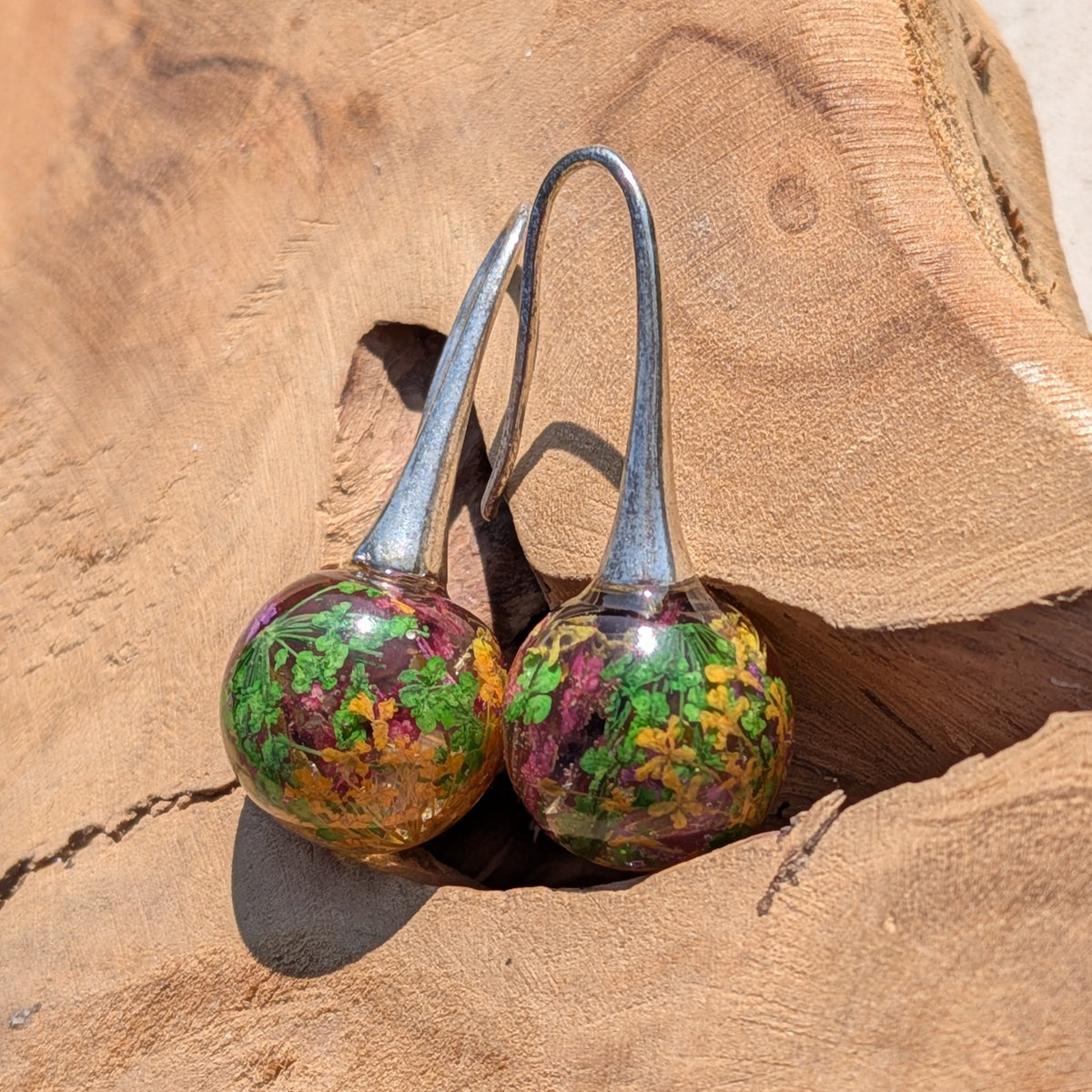Real dried flower moss resin ball earrings 12mm on textured surface, EL Creations