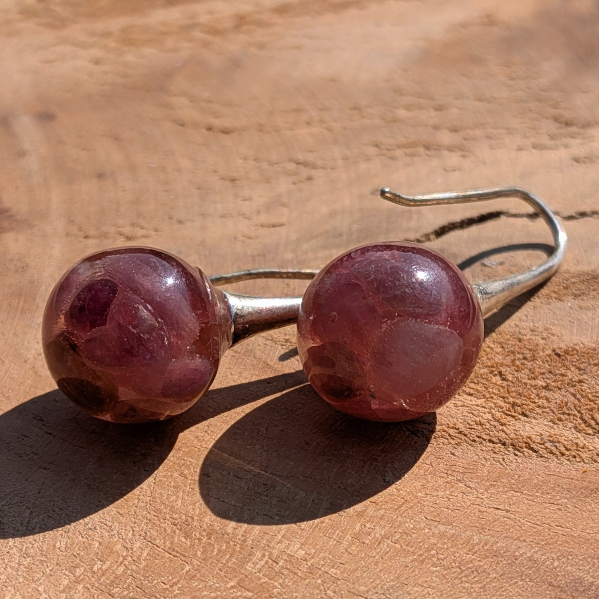 Close-up of pink tourmaline gemstone inside clear resin ball earrings, botanical jewelry EL Creations