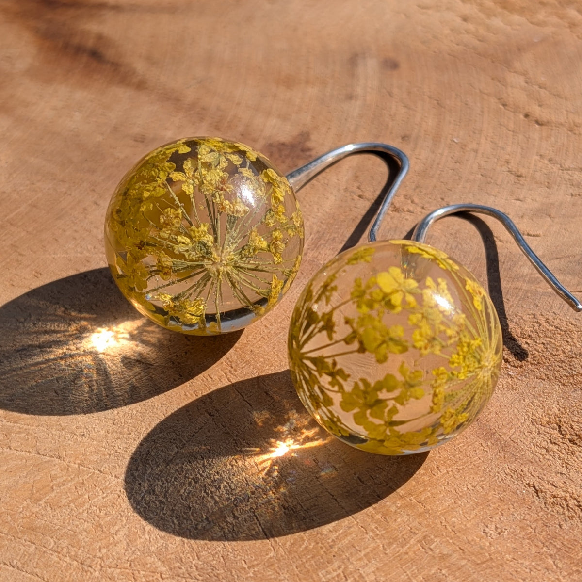 Yellow dried flower resin ball earrings top view, cheerful botanical dangle jewelry handmade in Belgium