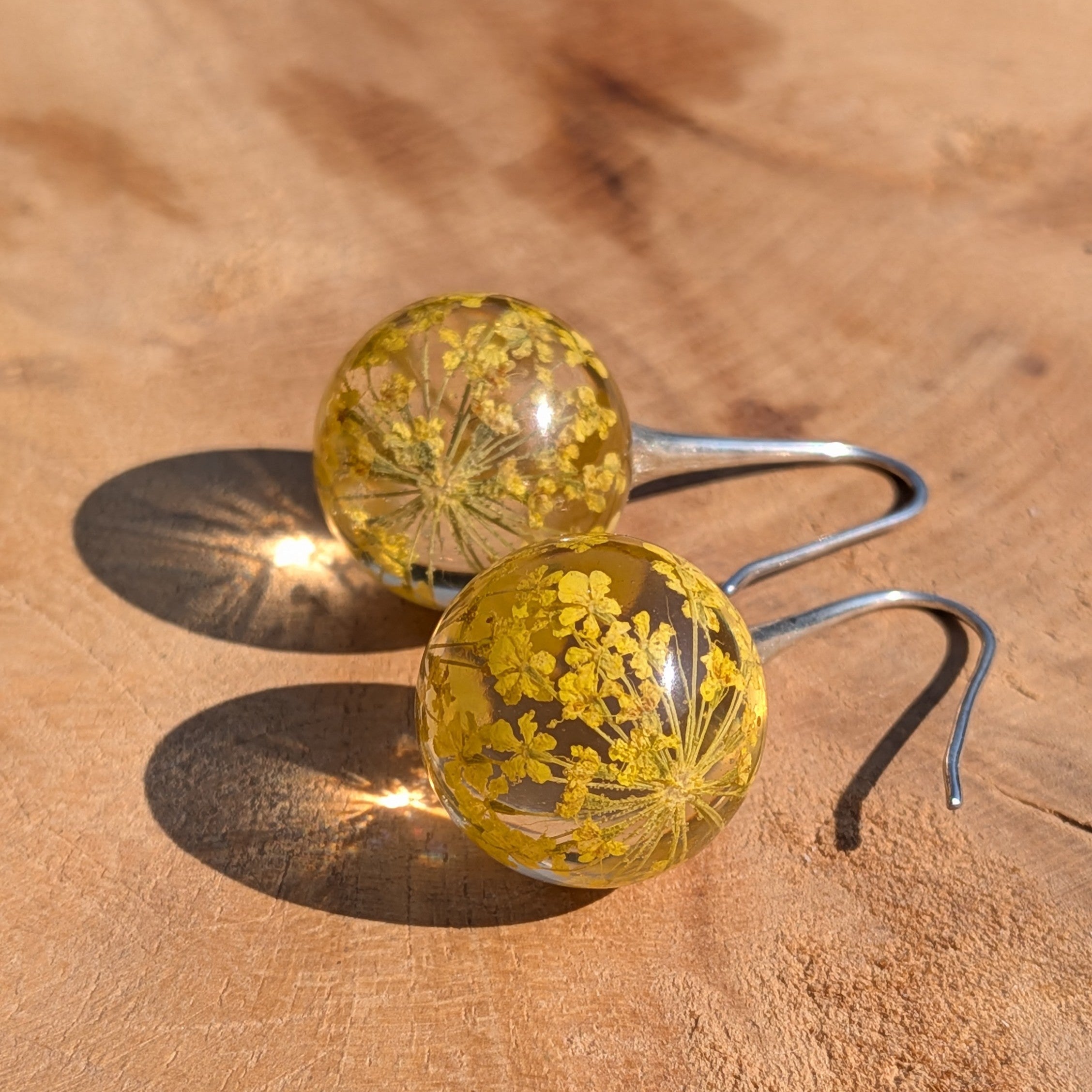 Pair of earrings with yellow floral elements on a wooden surface