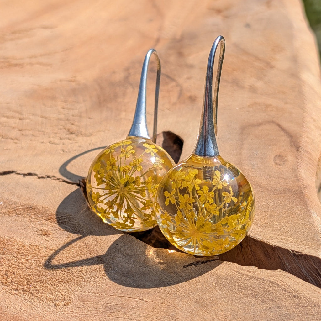 Glass earrings with floral contents on a wooden surface