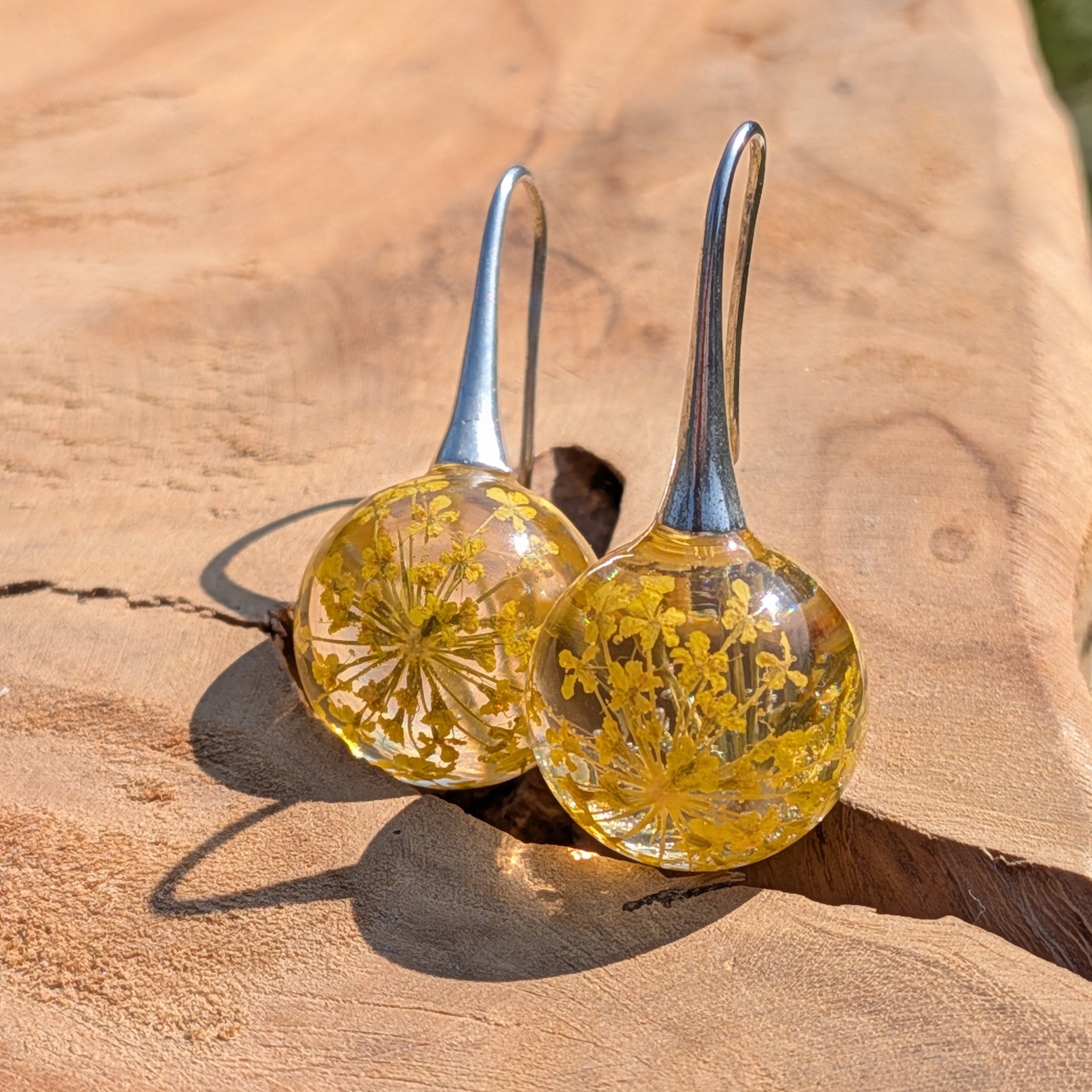 Glass earrings with floral contents on a wooden surface