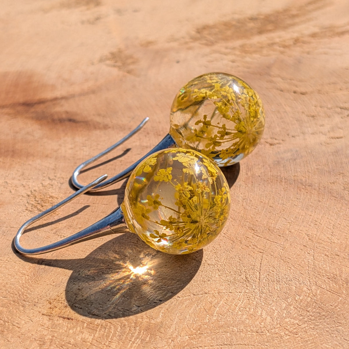 Handmade yellow flower resin ball earrings held between fingers, 3.5cm dangle jewelry EL Creations Belgium