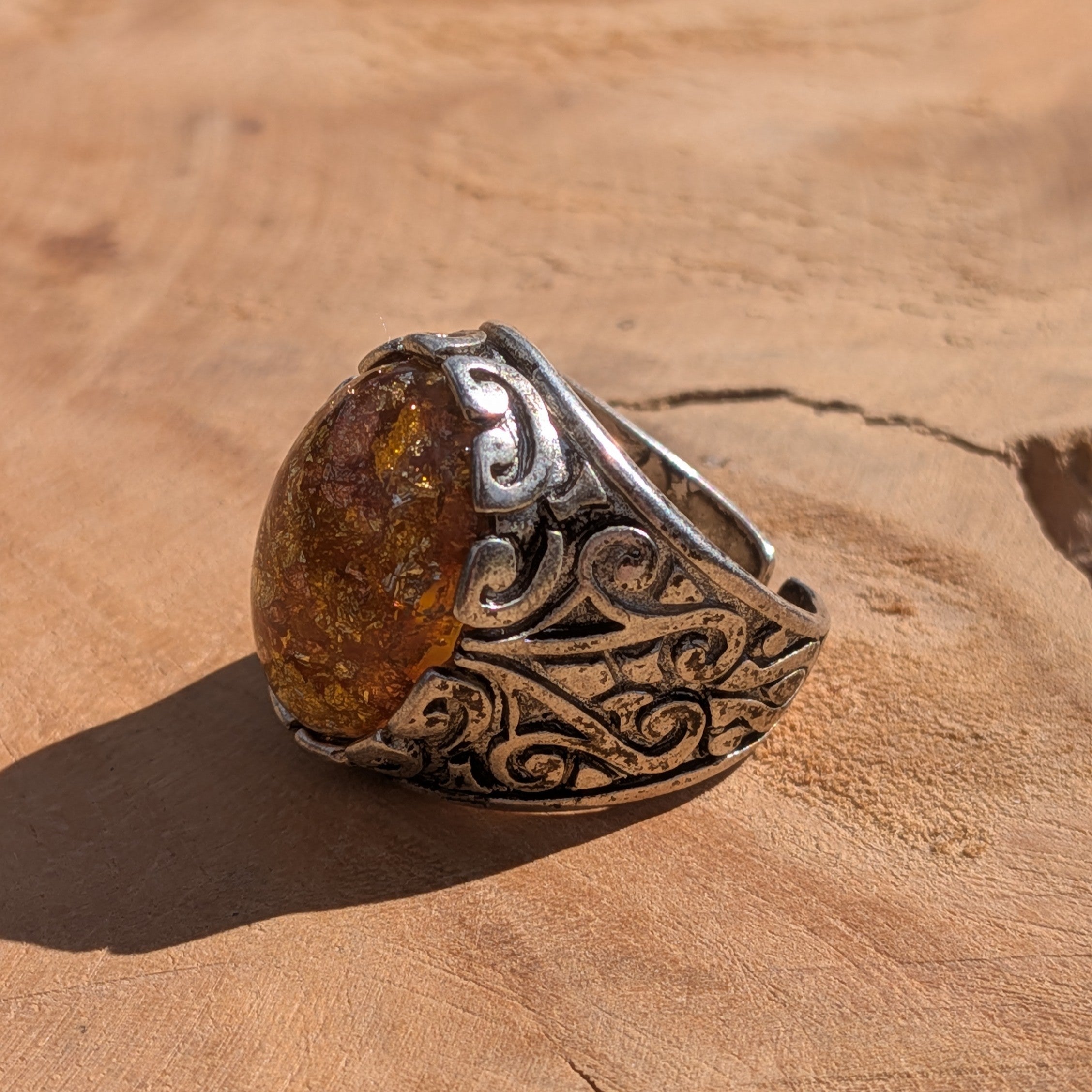 Amber resin ring antique bronze scrollwork band diagonal view on stone – EL-Creations