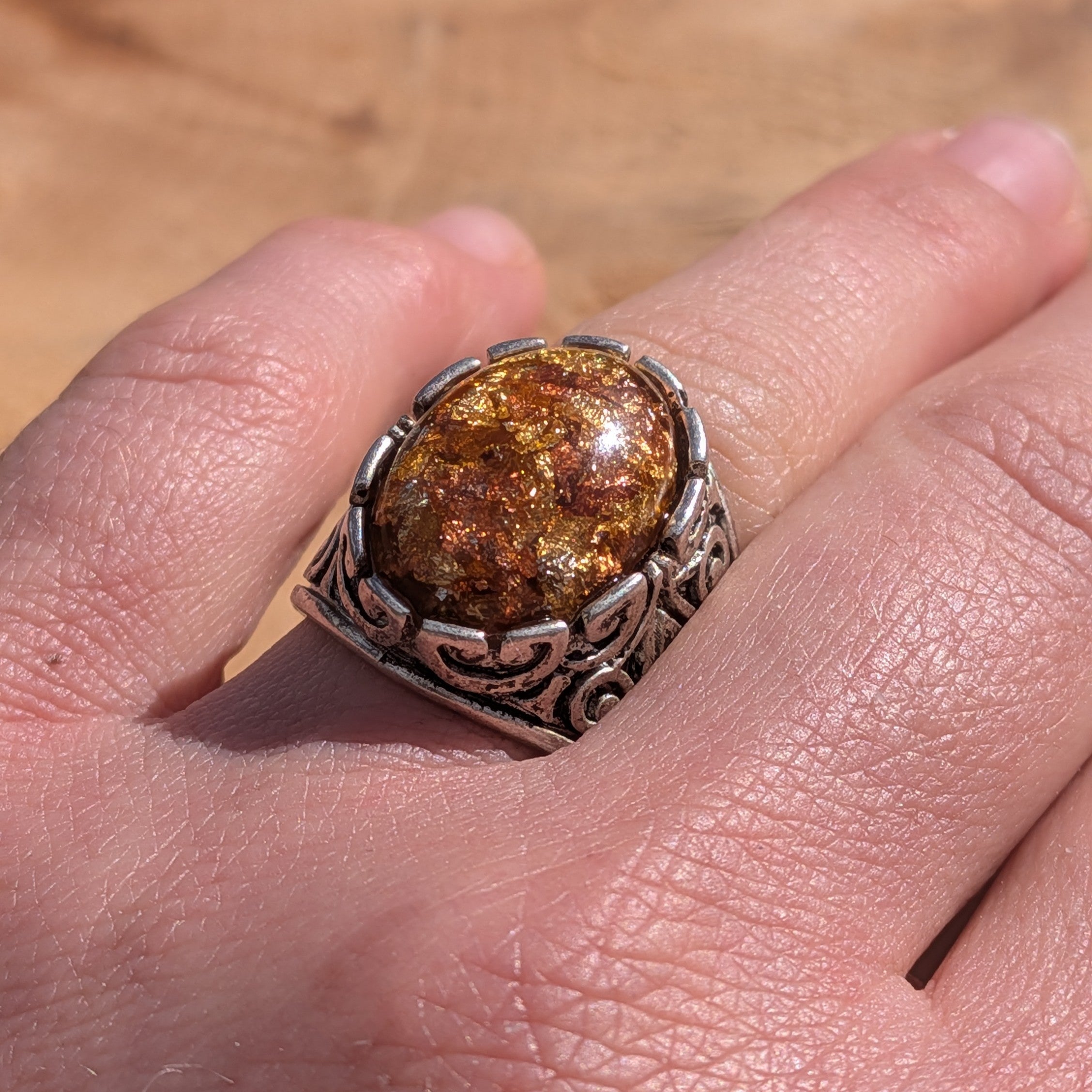 Amber resin ring antique bronze filigree base worn on hand close-up warm tones – EL-Creations