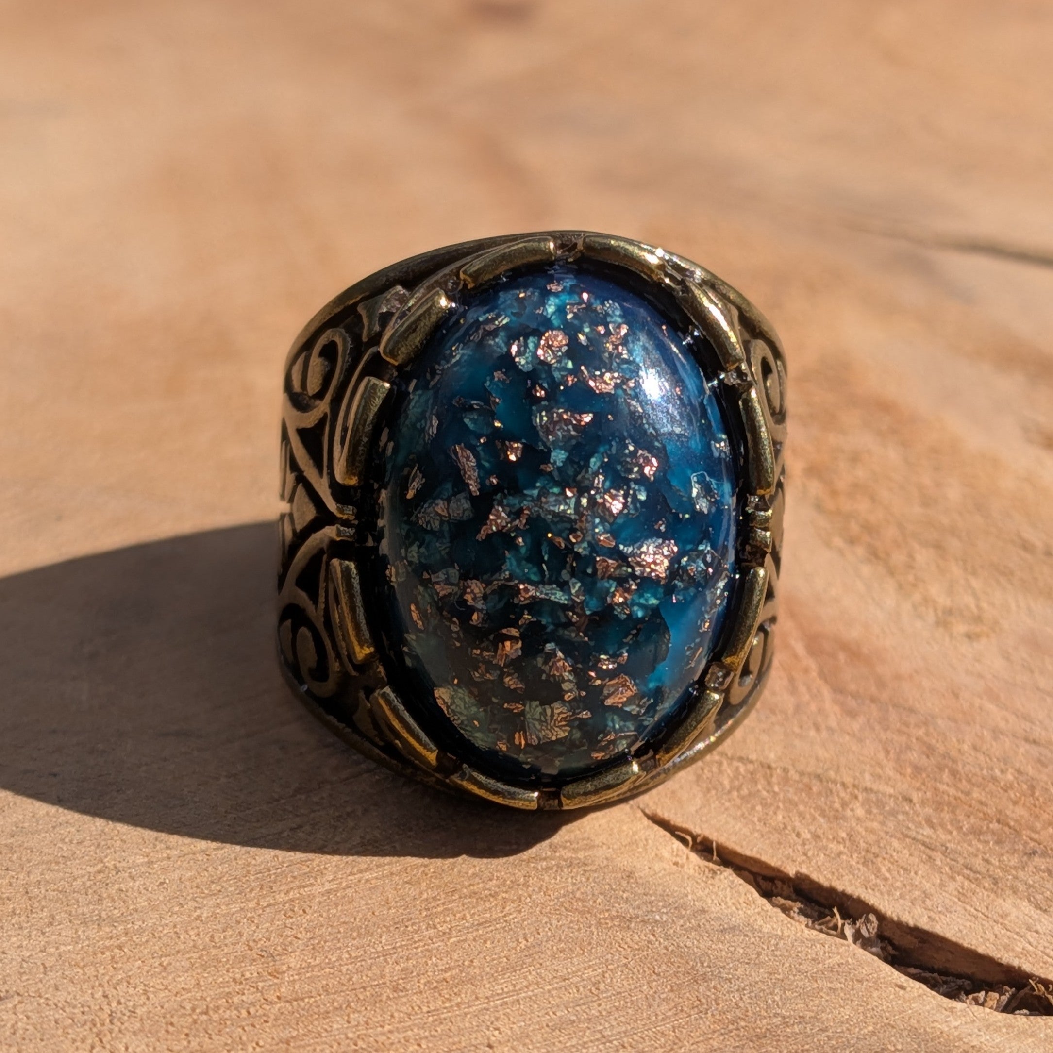 Teal blue resin ring antique bronze wide filigree scrollwork front view on wood in sunlight – EL-Creations