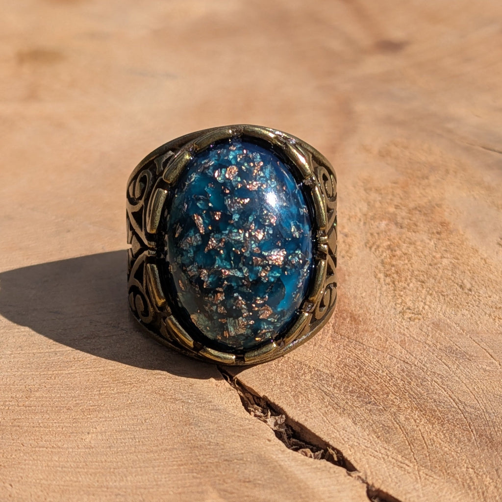 Teal blue resin ring antique bronze filigree band front view on wood warm light – EL-Creations