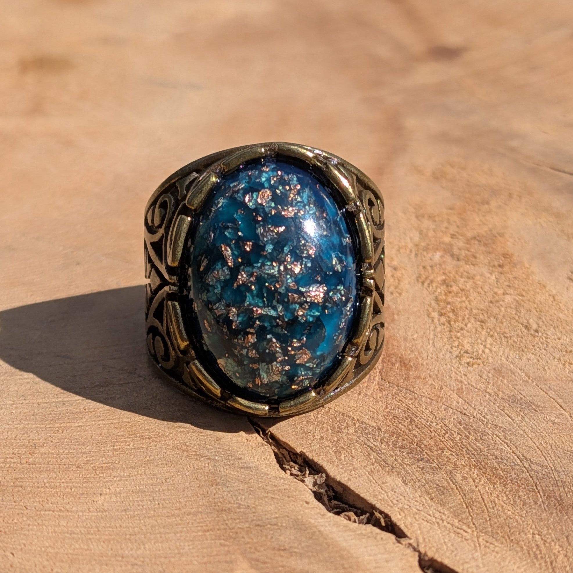 Teal blue resin ring antique bronze filigree band front view on wood warm light – EL-Creations