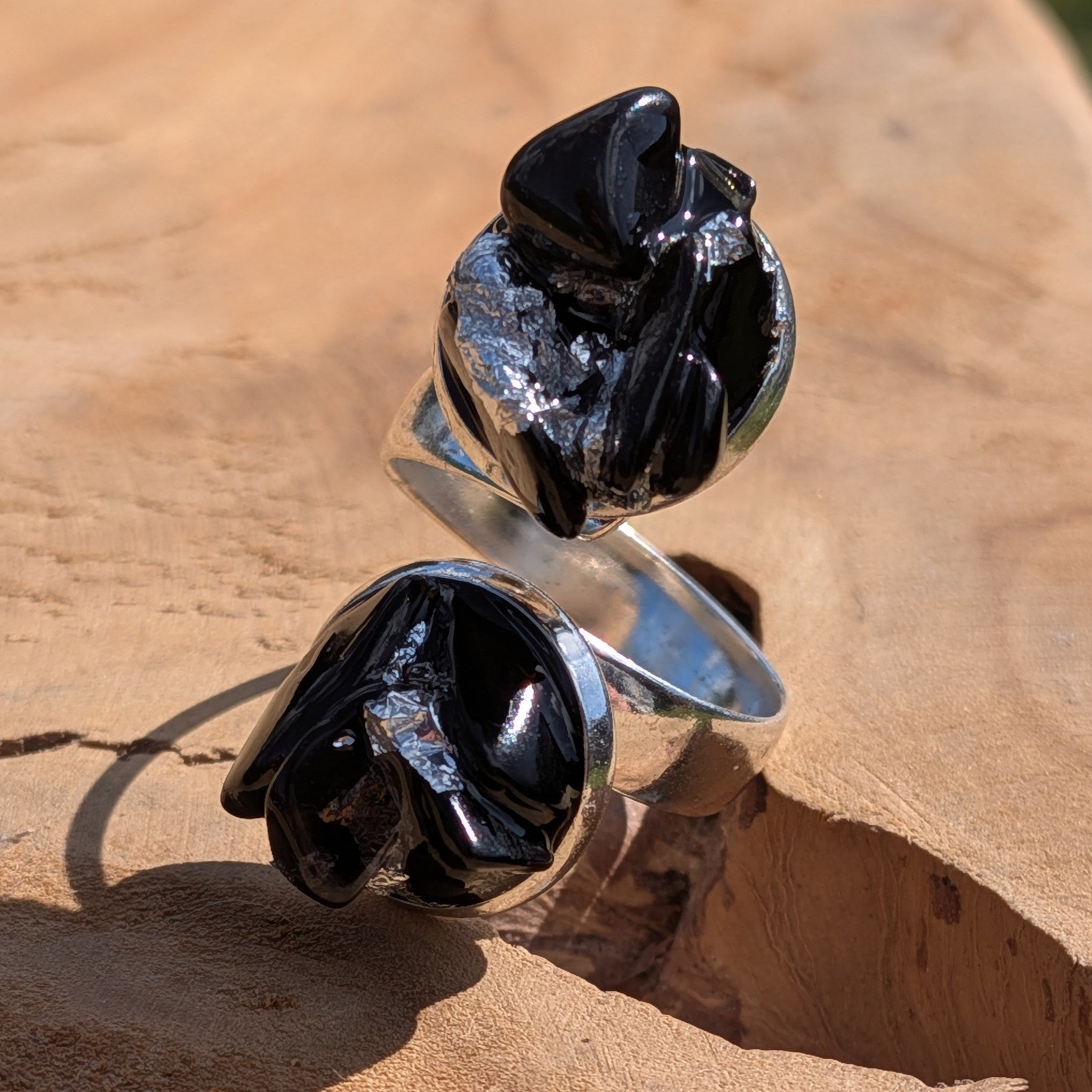 Handcrafted black obsidian raw stone rings on sandy rock, angled view – EL-Creations