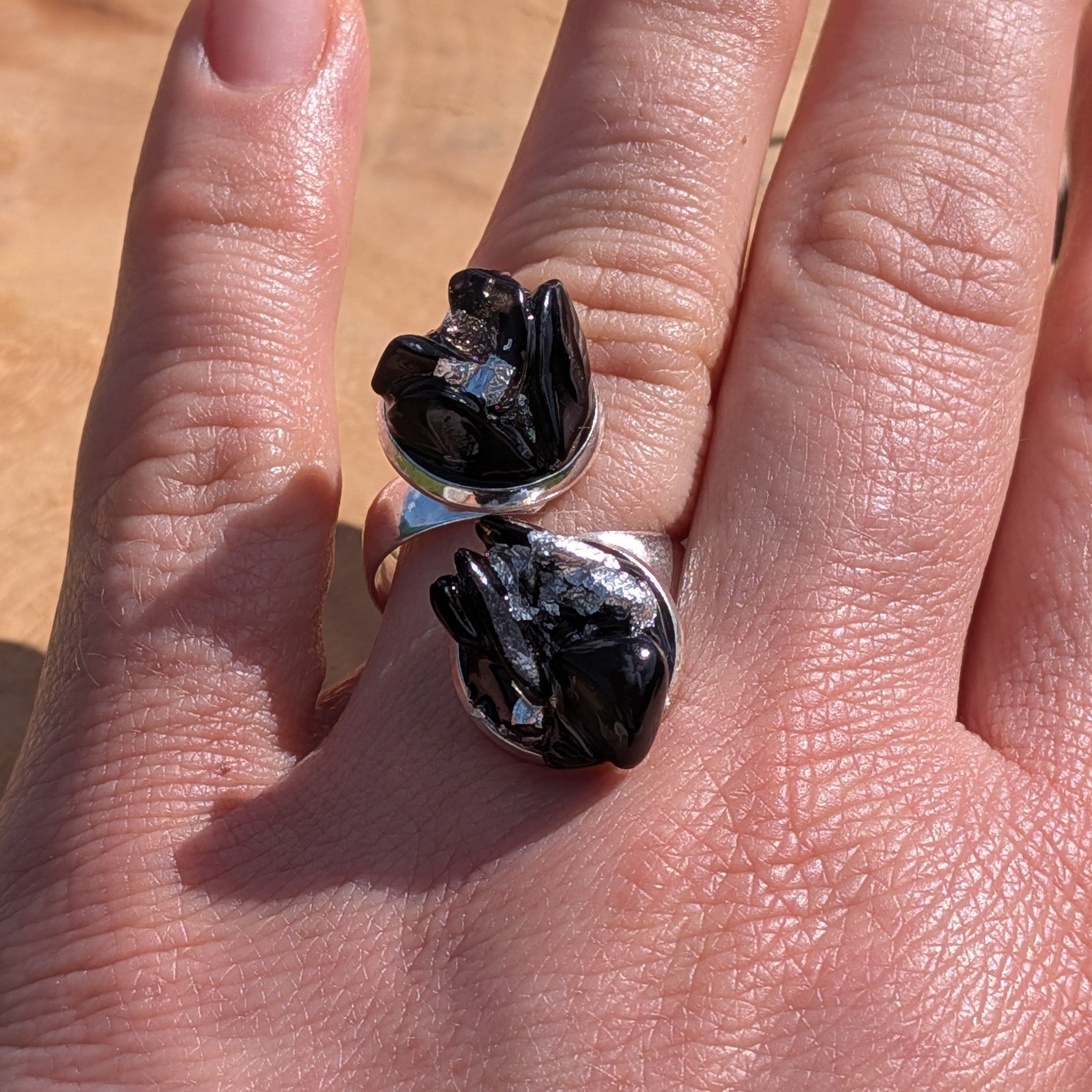 Two black onyx obsidian raw stone rings on sandy stone surface, silver alloy base side view – EL-Creations