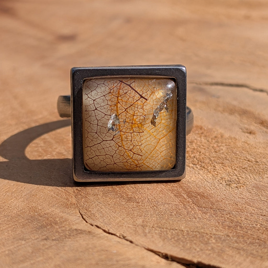 Skeleton leaf resin ring on wood, 15mm square gunmetal stainless steel bezel with copper and gold flakes – EL-Creations