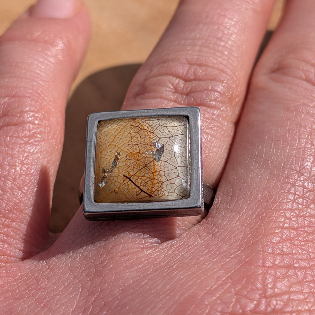 Top view of skeleton leaf resin ring on wood, amber leaf with copper and gold flakes in square steel bezel – EL-Creations