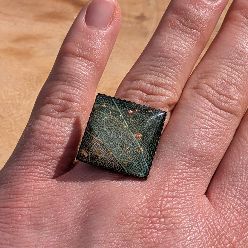 Handcrafted skeleton leaf resin ring on hand, adjustable bronze band with copper and gold flakes in dark resin – EL-Creations