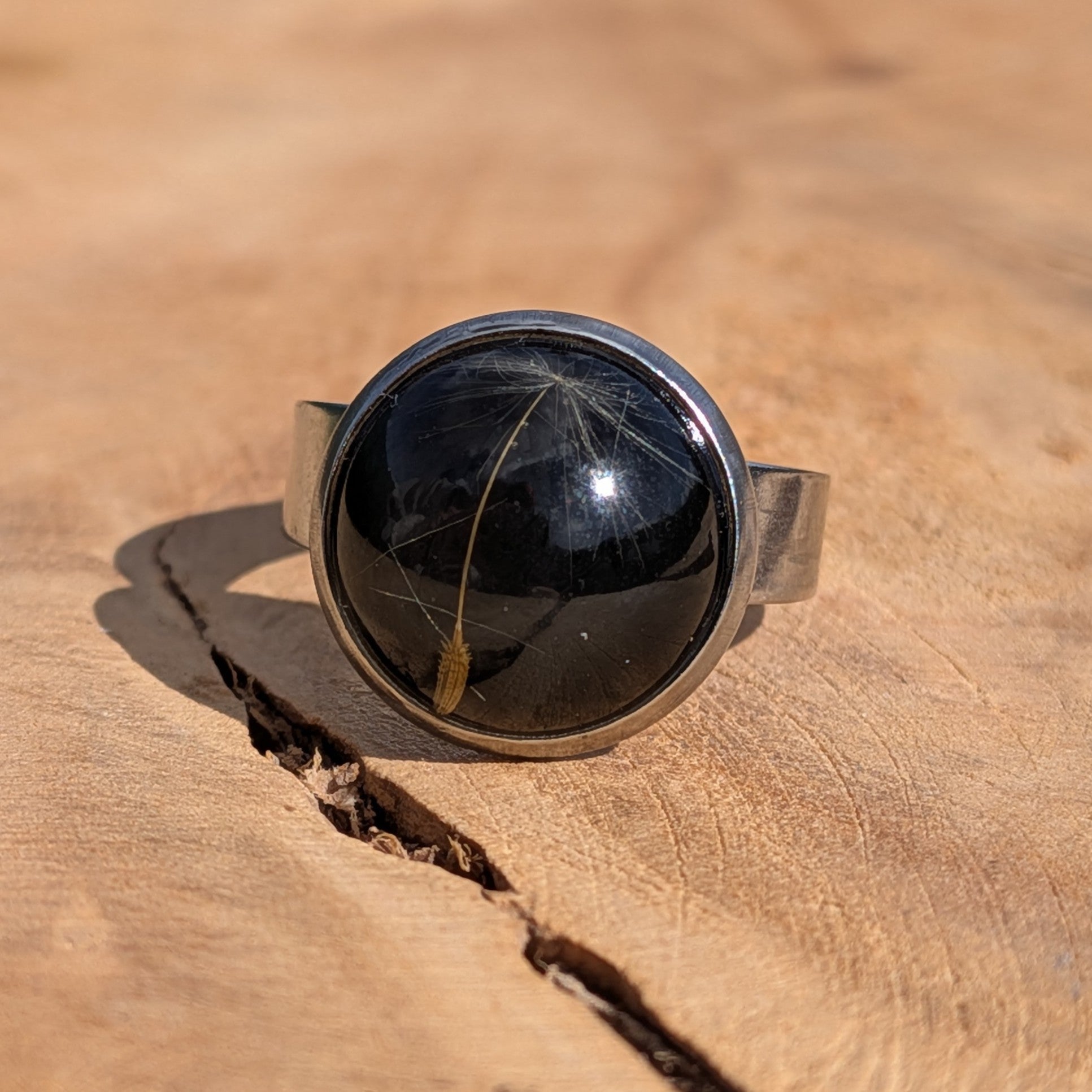 Black dandelion seed resin ring worn on finger, close-up of 14mm round stainless steel bezel – EL-Creations