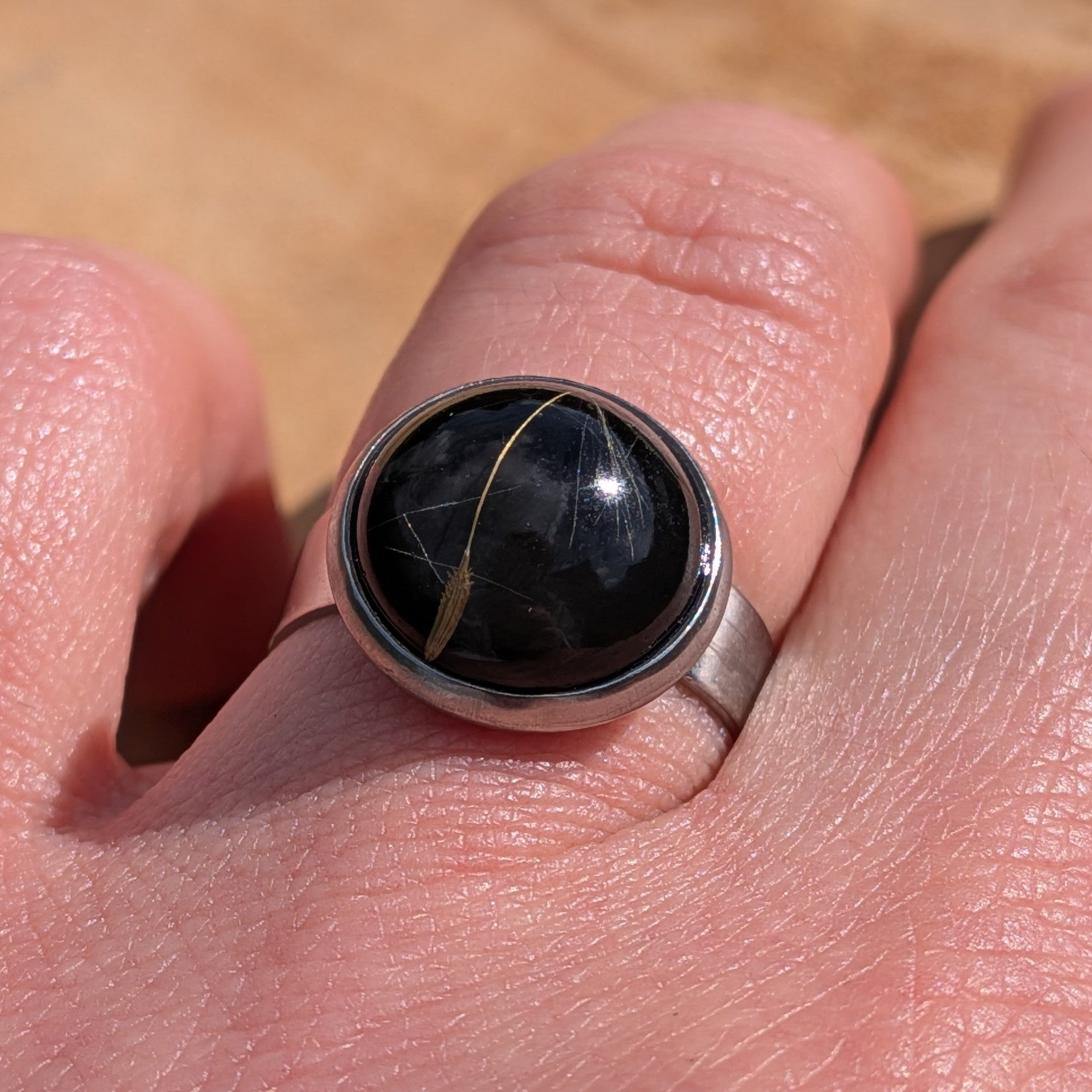 Side view of black botanical resin ring on hand, dandelion seeds in wide stainless steel band – EL-Creations