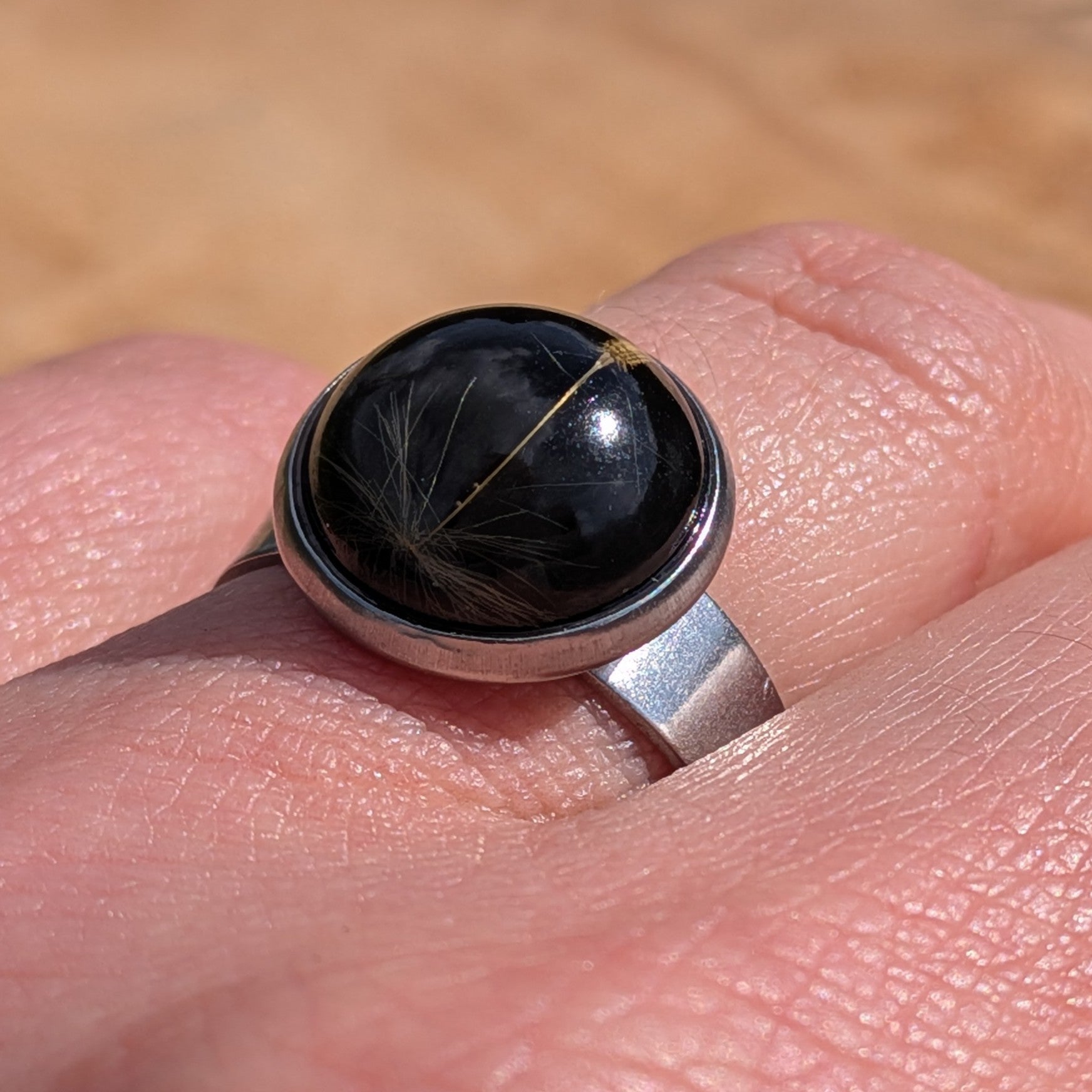 Handcrafted black dandelion seed resin ring on hand, 14mm round stainless steel setting – EL-Creations