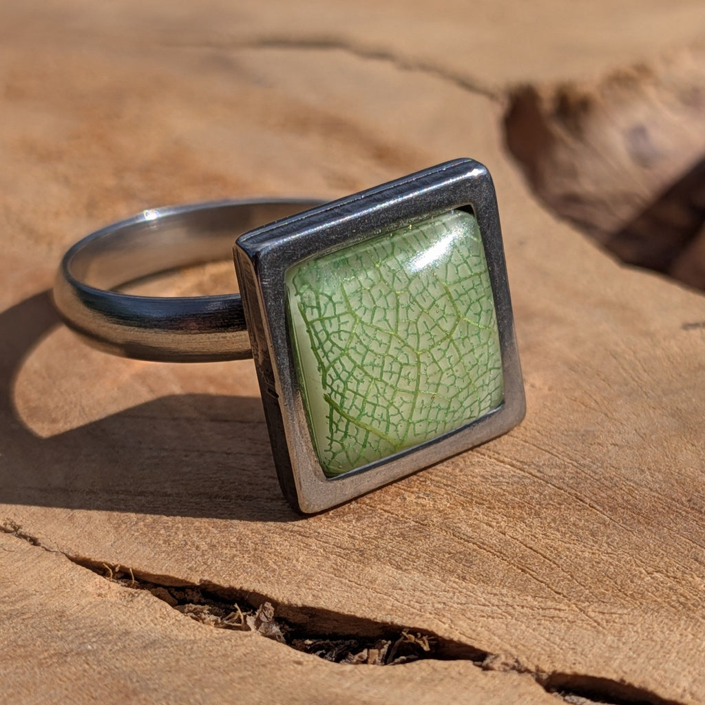 Close-up of green botanical resin ring on wood, skeleton leaf in sage green square stainless steel setting – EL-Creations