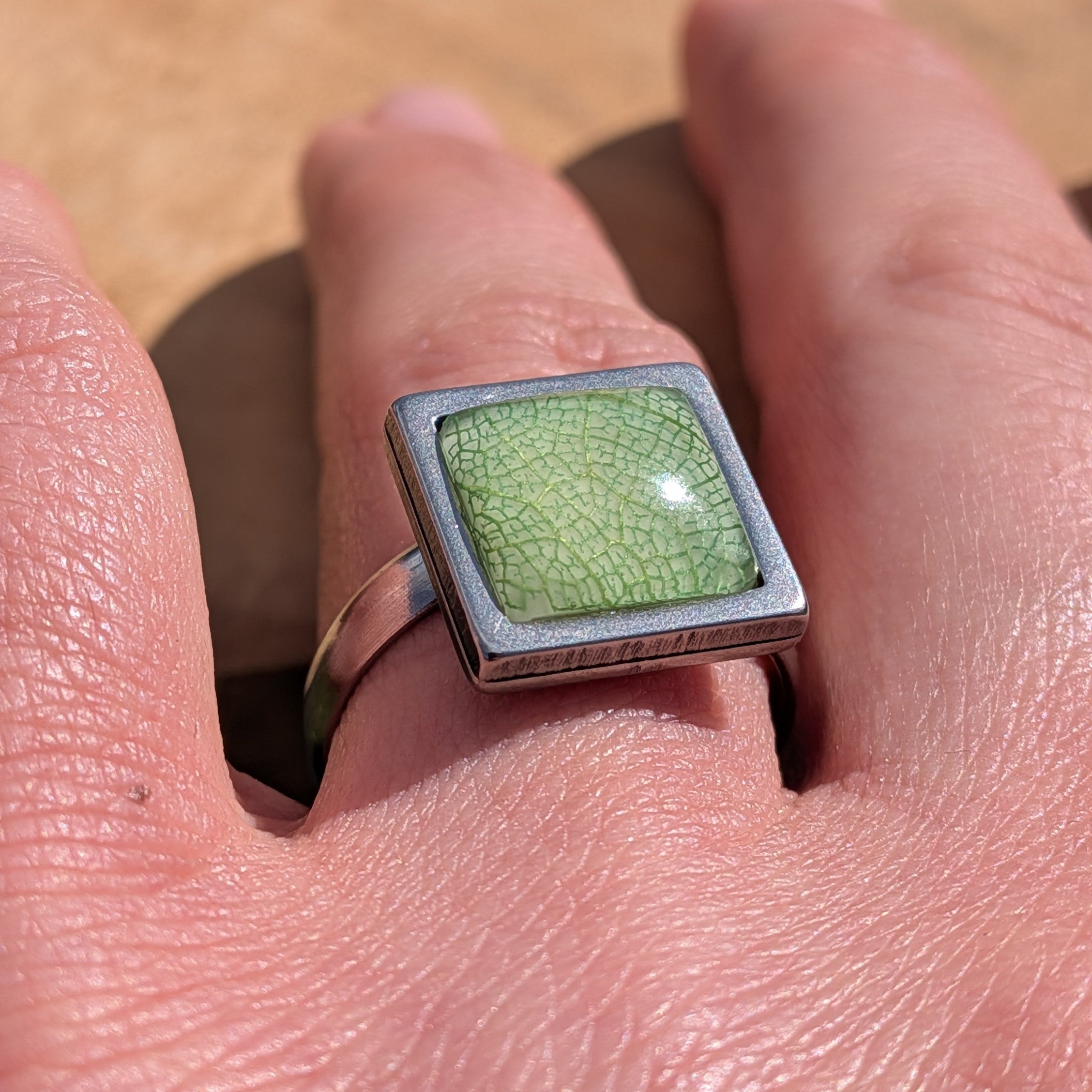 Top view of sage green resin ring on hand, skeleton leaf detail in 14mm square stainless steel setting – EL-Creations